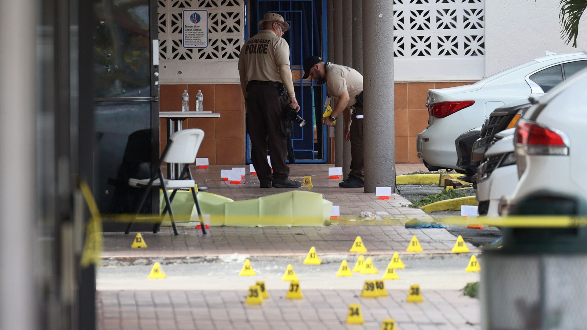 Police investigate shell case evidence markers. 