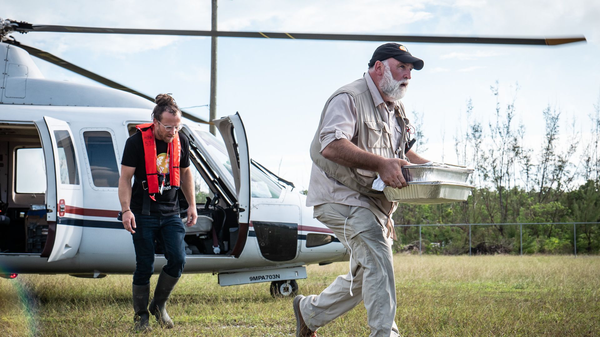 A man runs carrying trays of food.