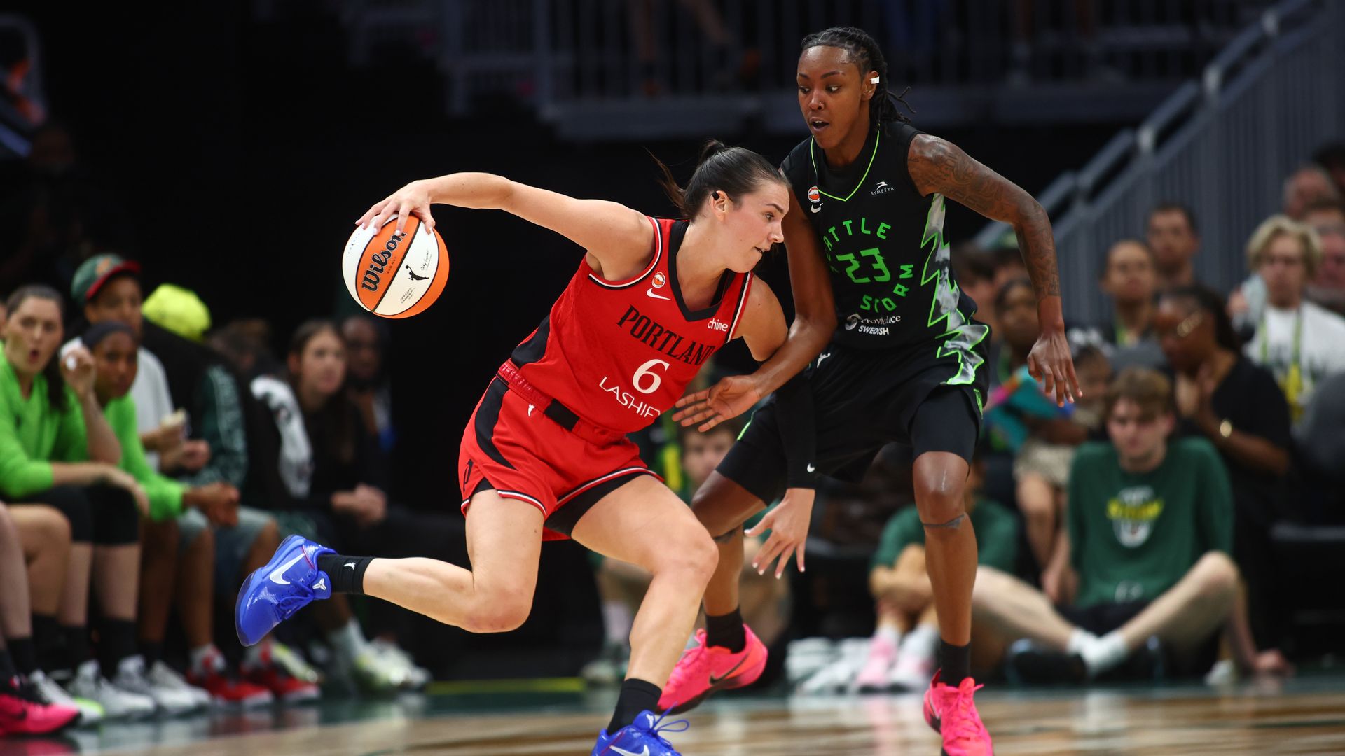 A Portland Fire guard drives past a Seattle Storm defender during a game at Climate Pledge Arena.