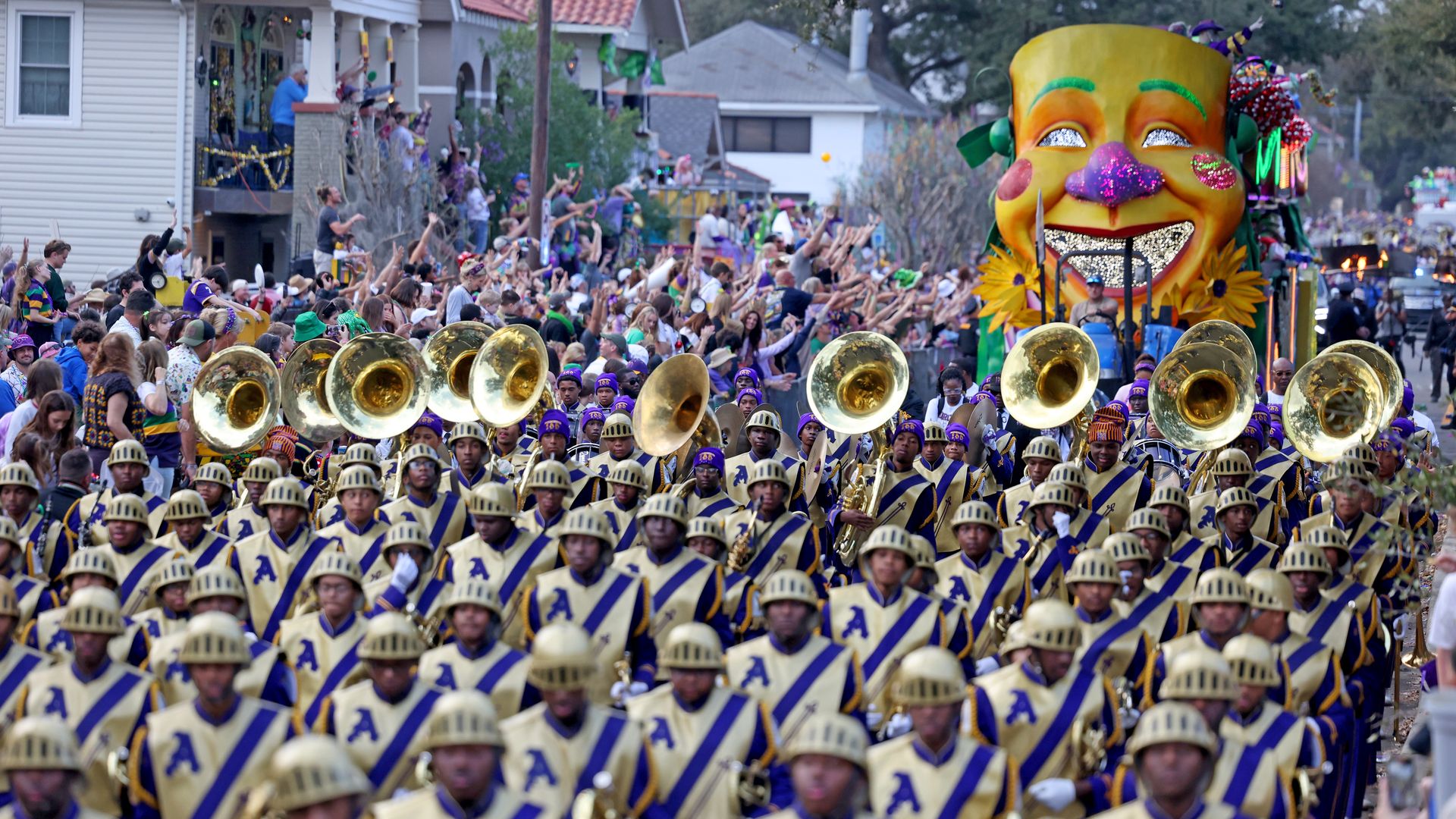 Photo shows the St. Augustine High School marching band with their instruments. They are marching in front of a Mardi Gras float in the Endymion parade.