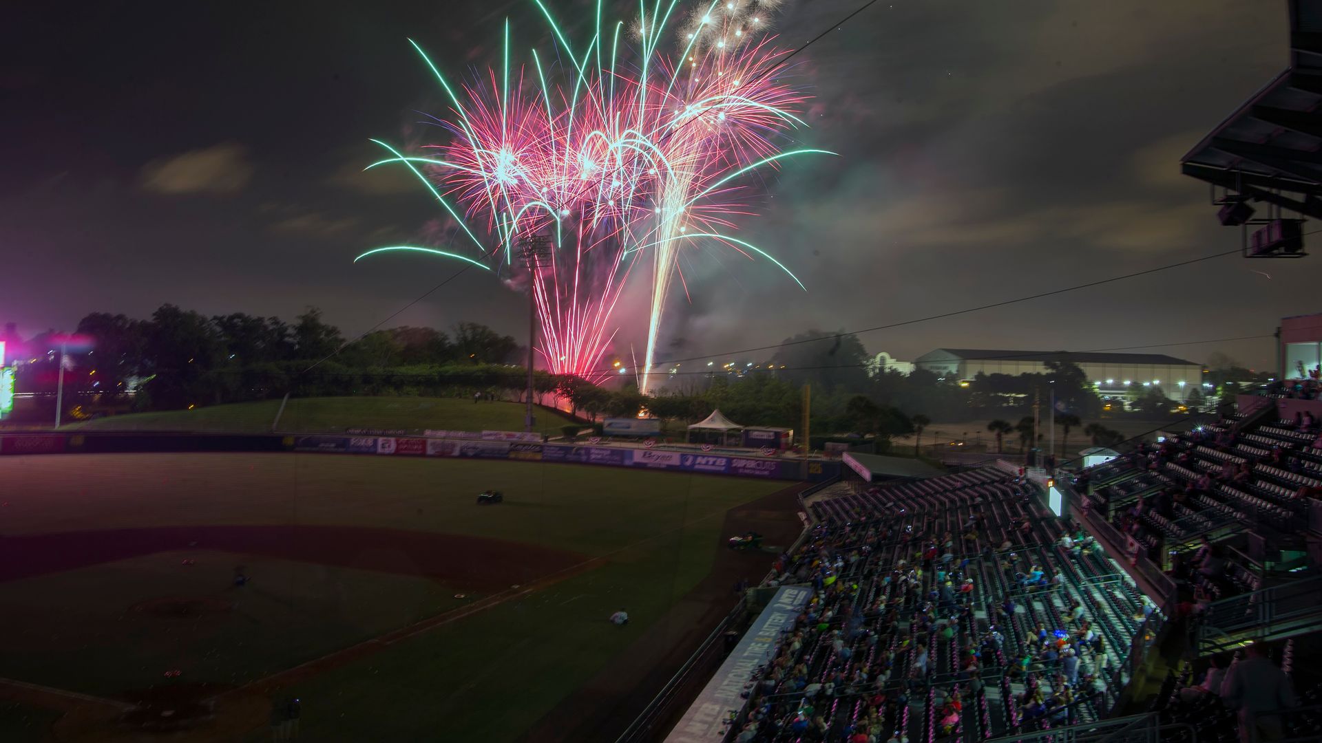 Fireworks light up the night sky over a baseball stadium.