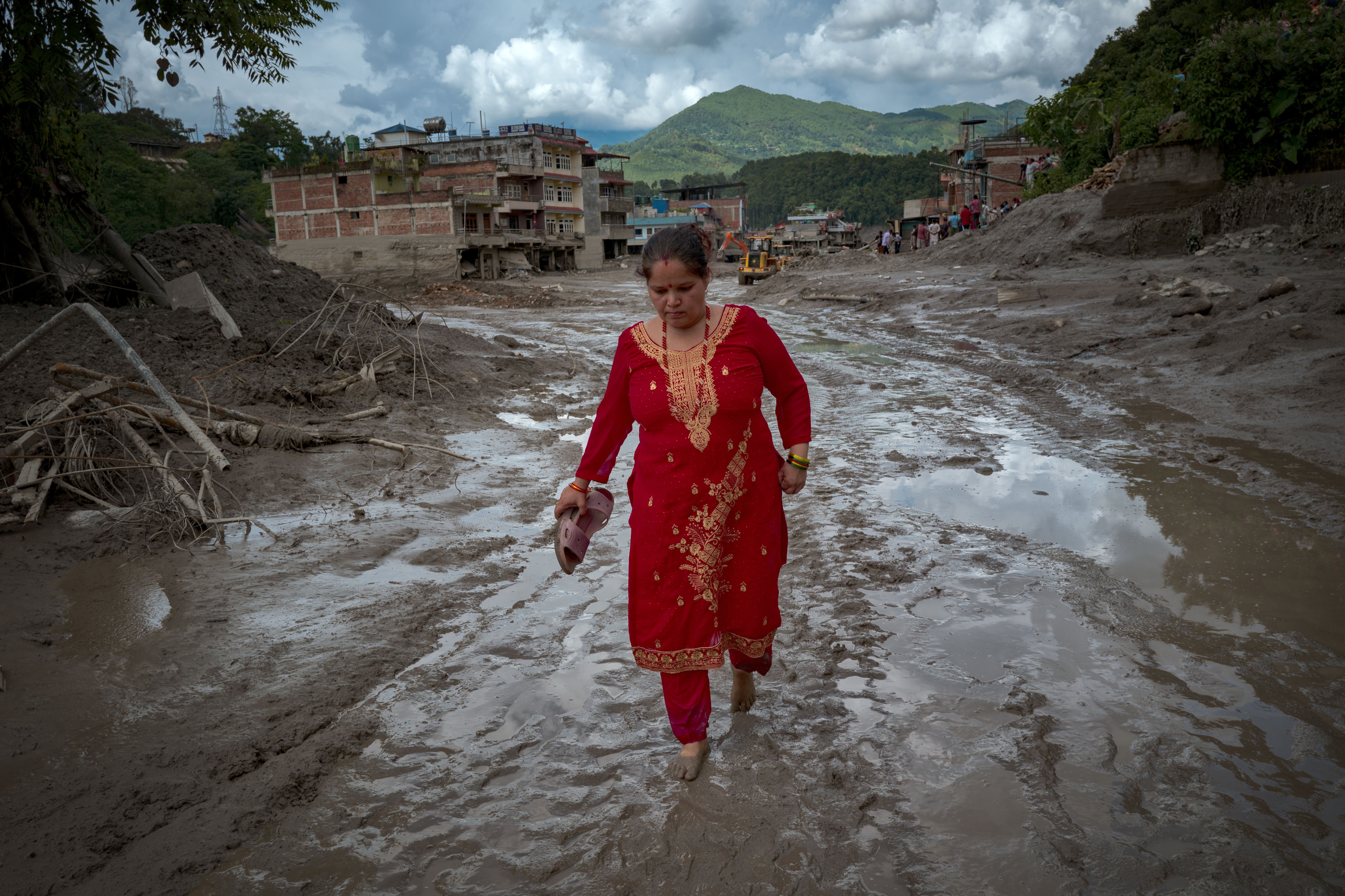A resident walks along a muddy road today following flash floods in Trishuli, Nepal. Photo: Ezra Acayan/Getty Images