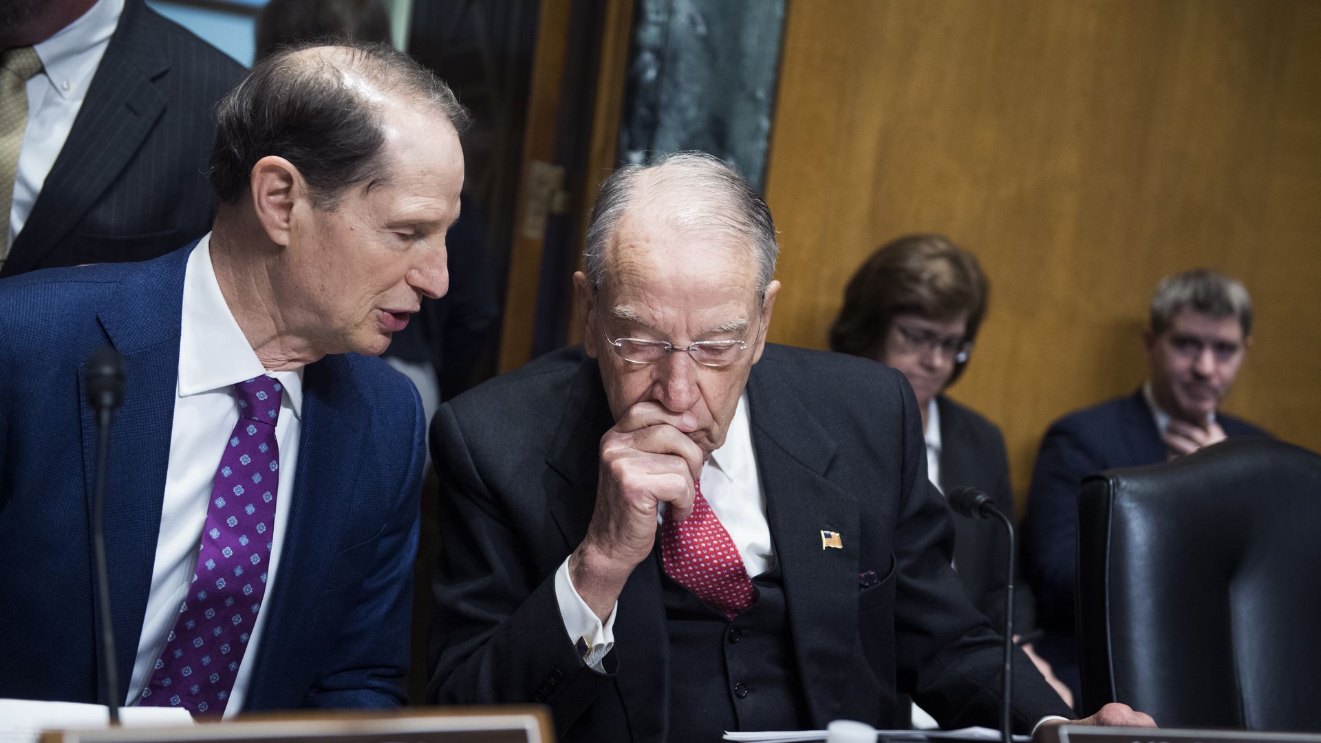 Sens. Ron Wyden and Chuck Grassley sit and talk at a hearing. 