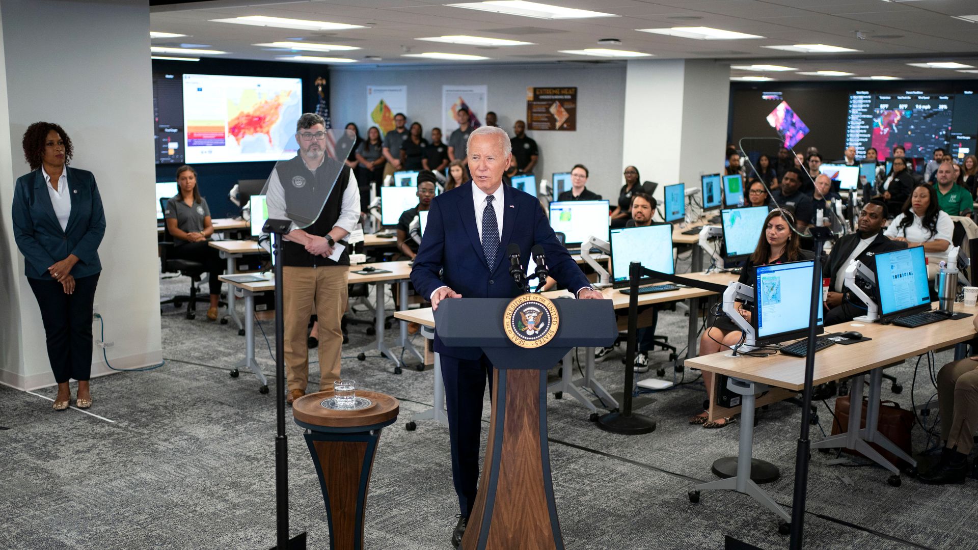 Joe Biden behind a podium with an emergency response center in the background.