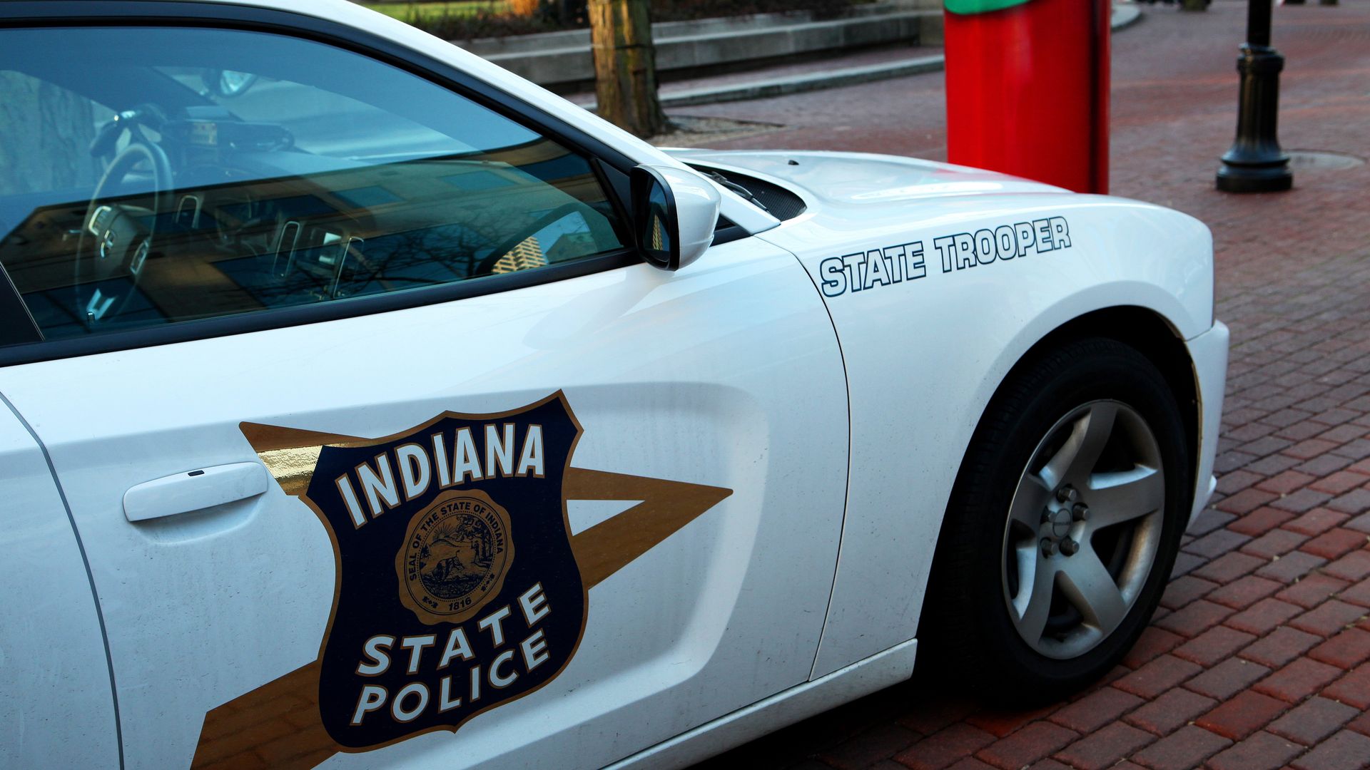 A white Indiana State Police Car is parked on Monument Circle.