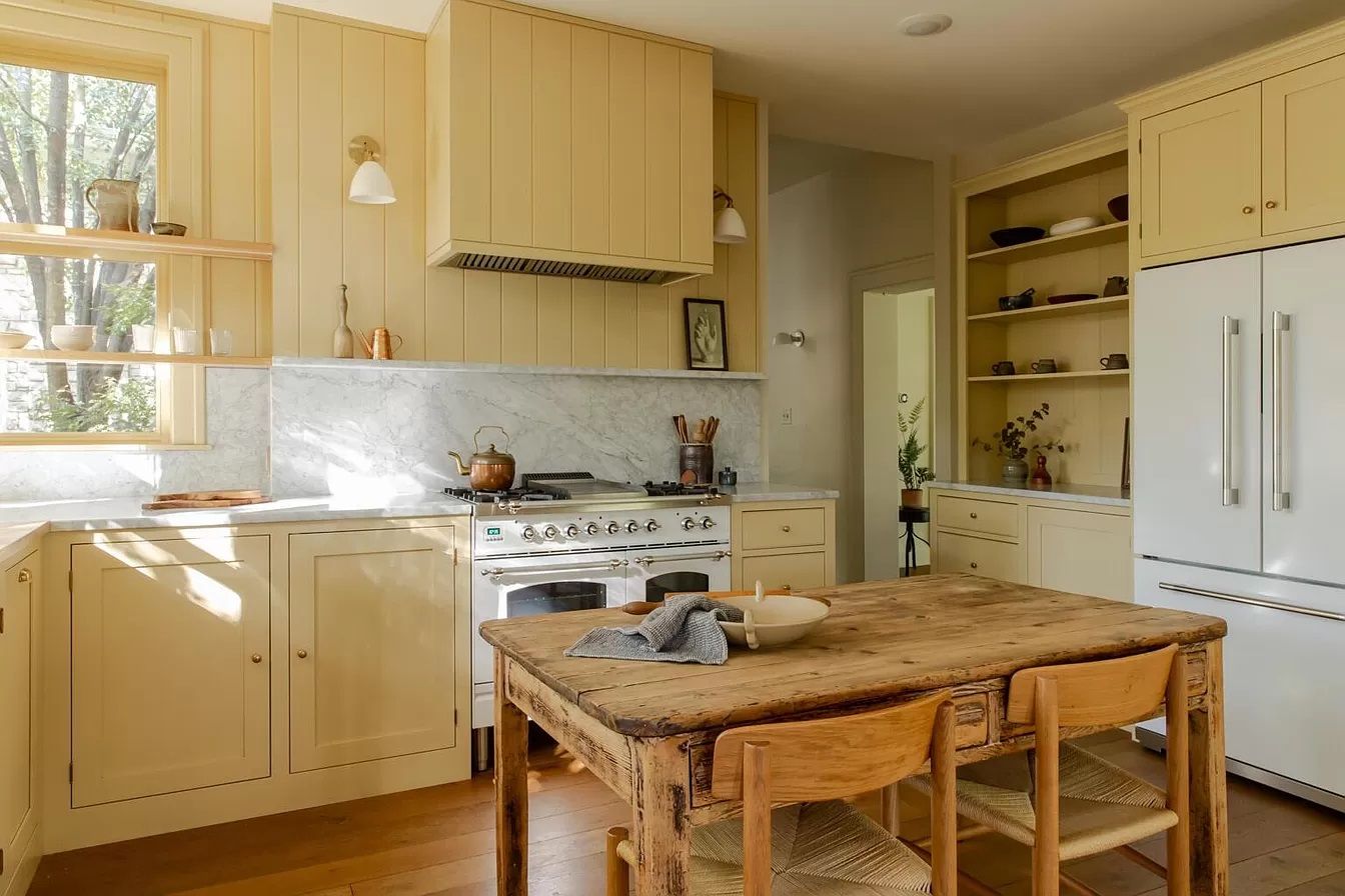 A home's kitchen with a table in the foreground and appliances in back. 