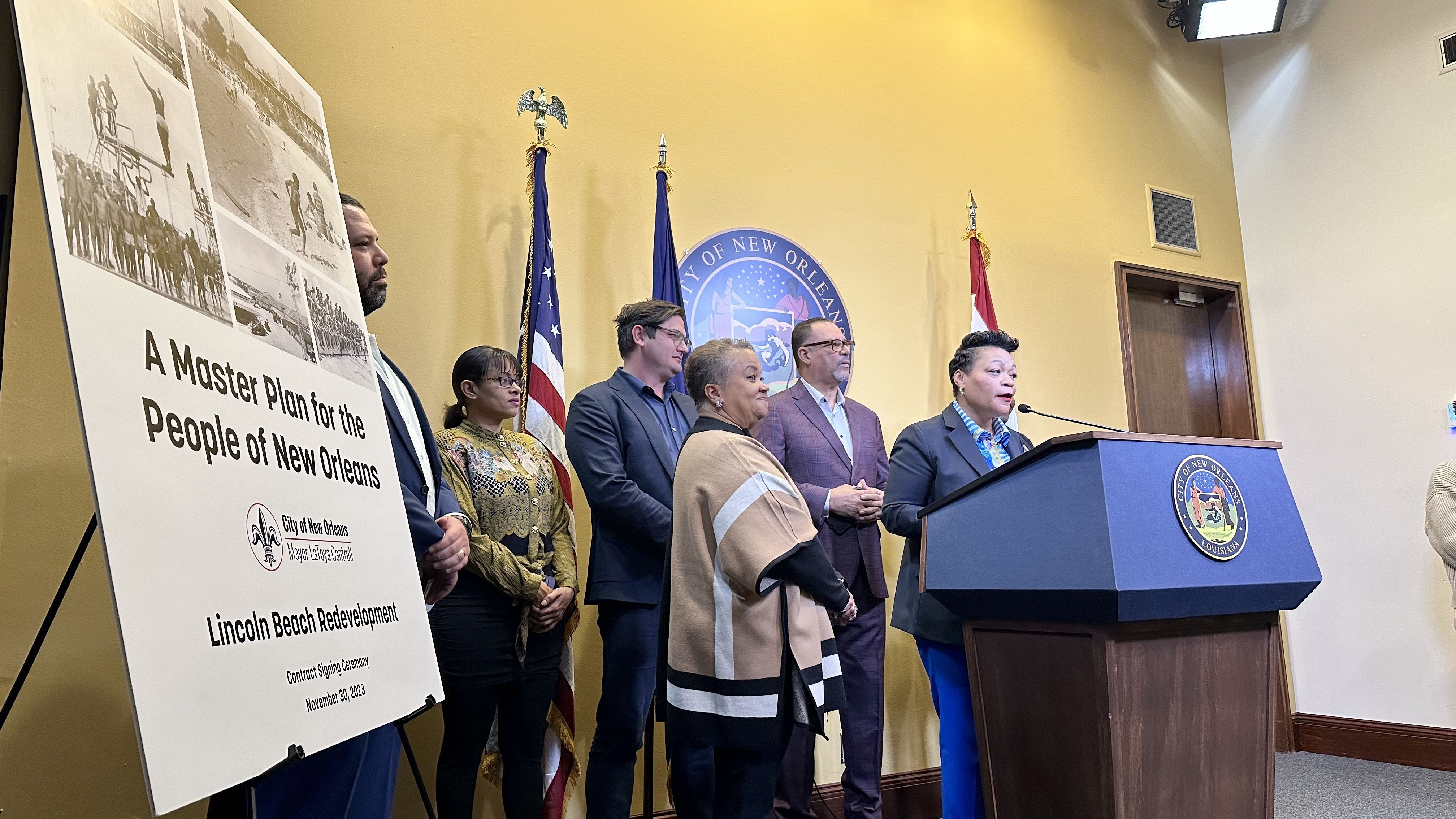 Mayor LaToya Cantrell was joined by Councilman Oliver Thomas and other dignitaries on Thursday, Nov. 30., 2023, to sign the contract for the Lincoln Beach master plan.  The photo shows them standing behind a podium with a sign about the master plan.