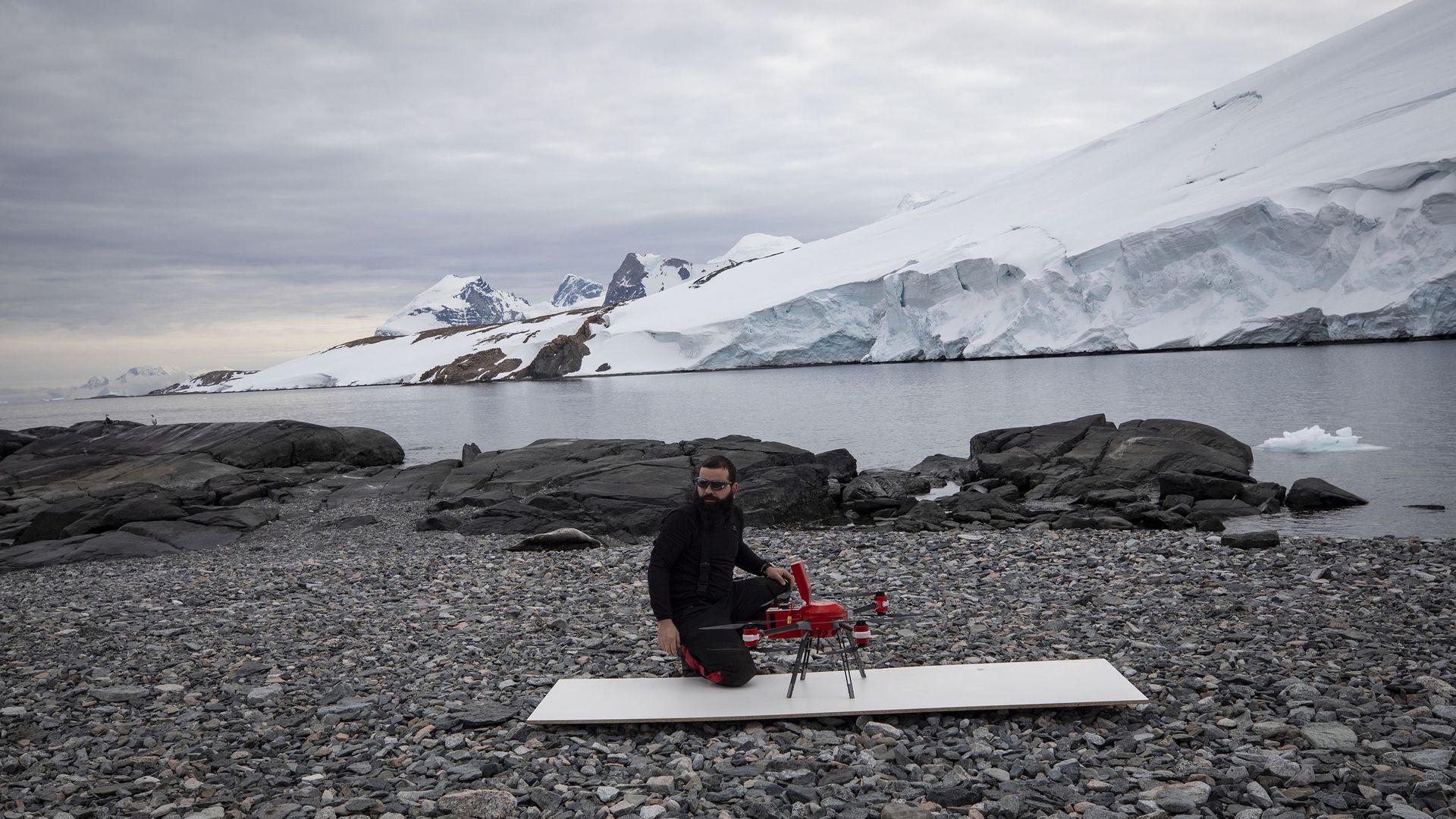 scientist sitting next to a lidar-equipped drone outdoors in Antarctica