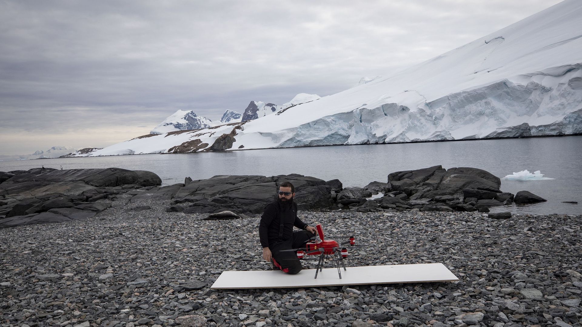 scientist sitting next to a lidar-equipped drone outdoors in Antarctica