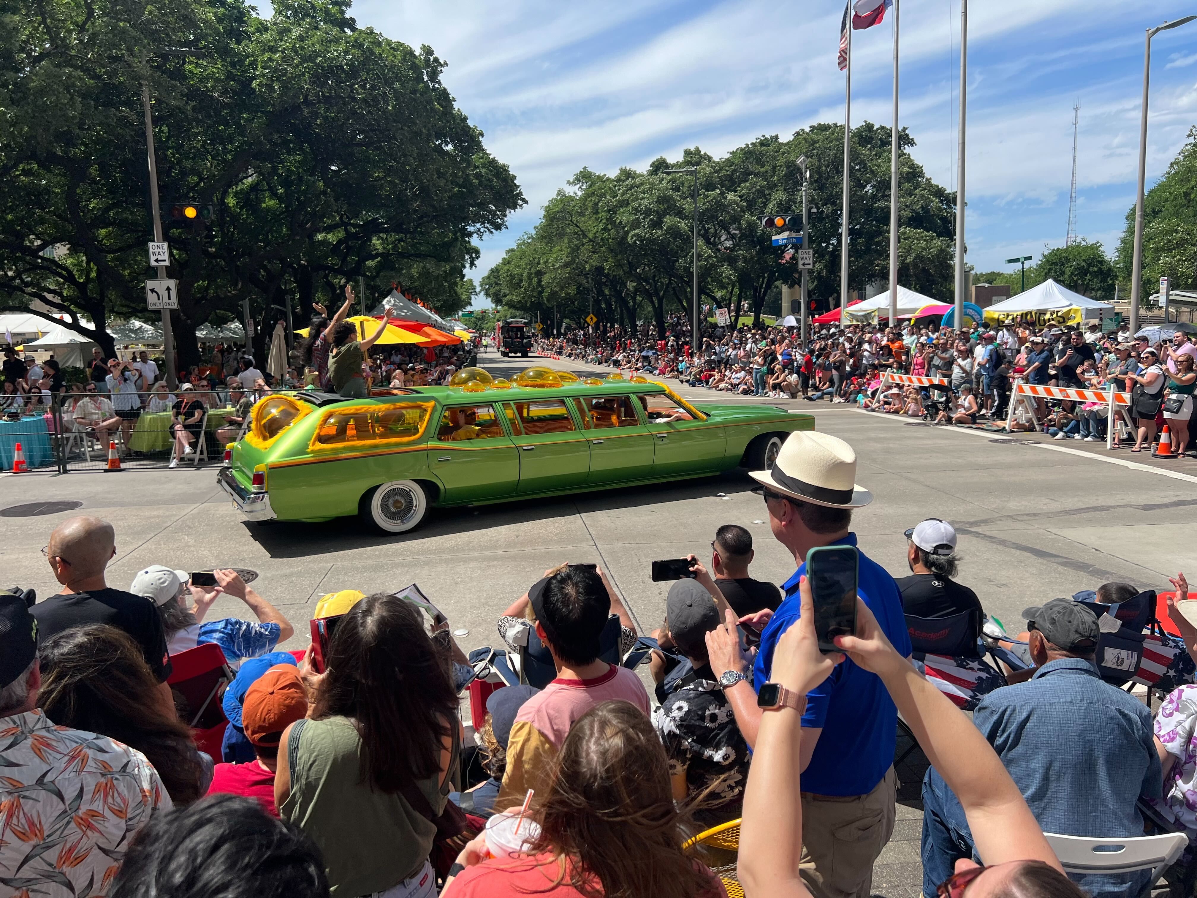 A crowd of people and a green long car