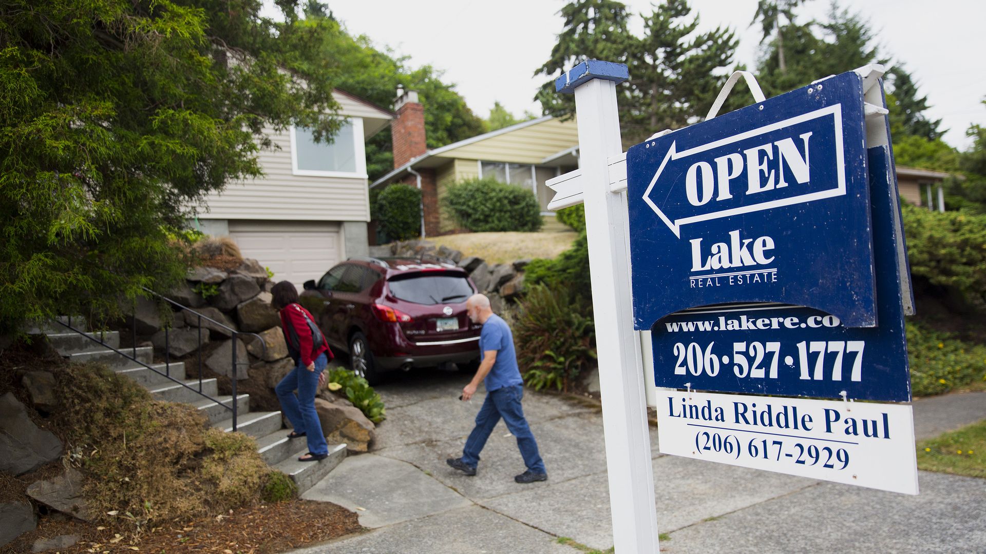 Two people walking into house in front of "open house" sign