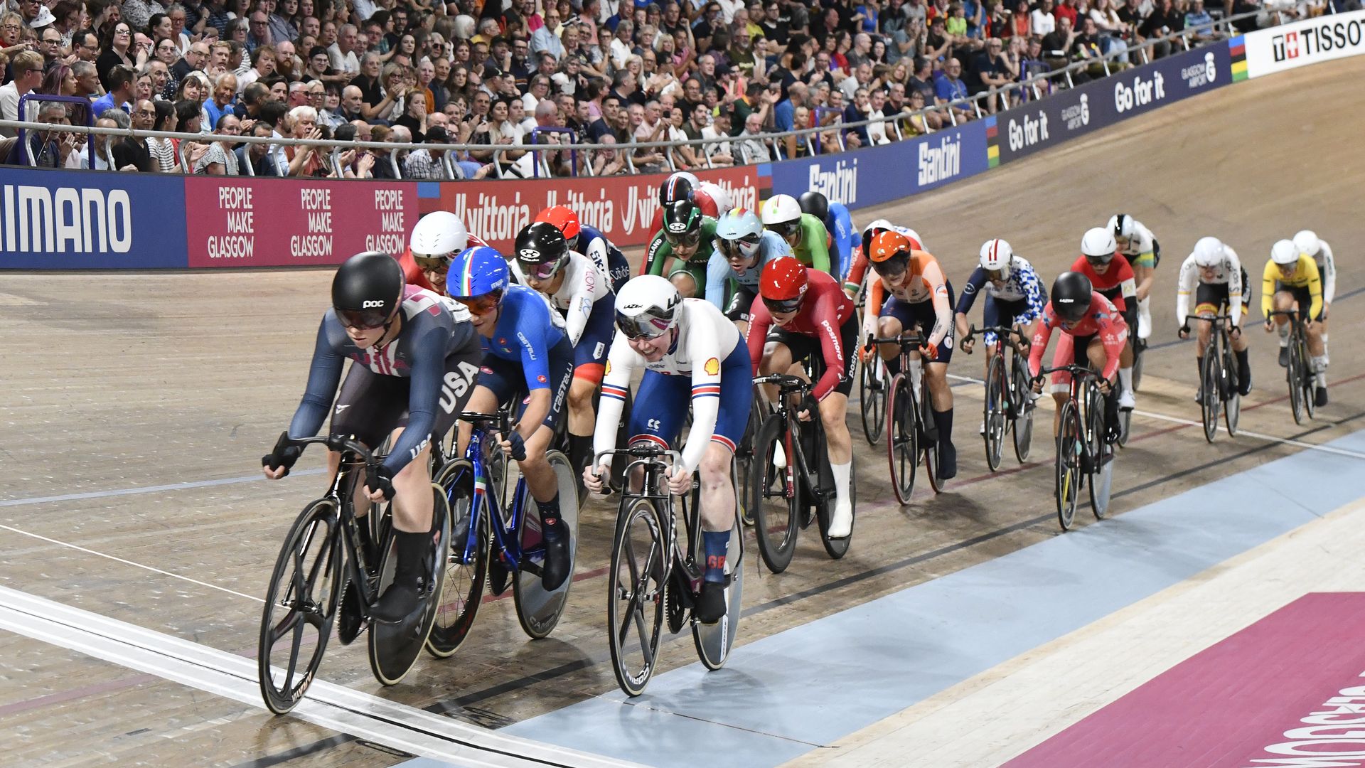 A group of cyclists ride close together on a track. 