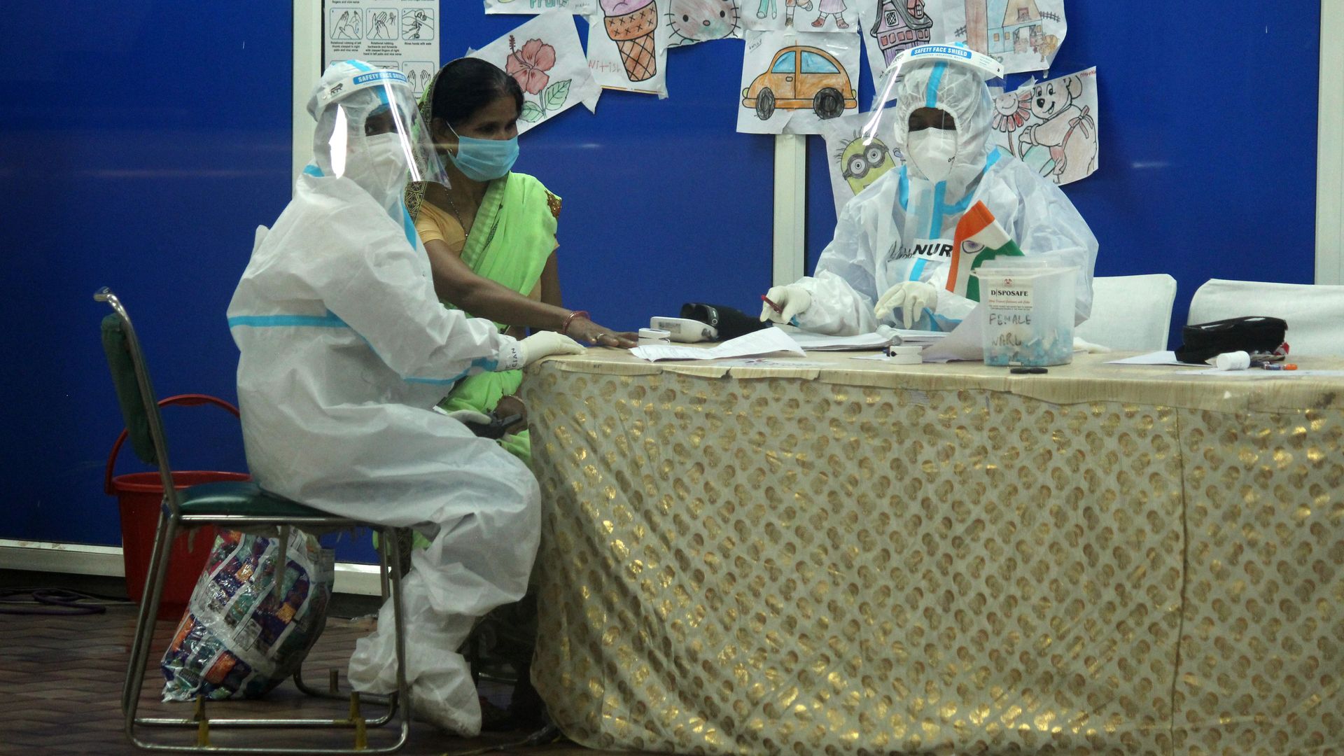A doctor covered in Personal Protective Equipment (PPE) kit, examines the patient inside female ward at Covid care facility inside Commonwealth Games Village Sports Complex, in New Delhi, India