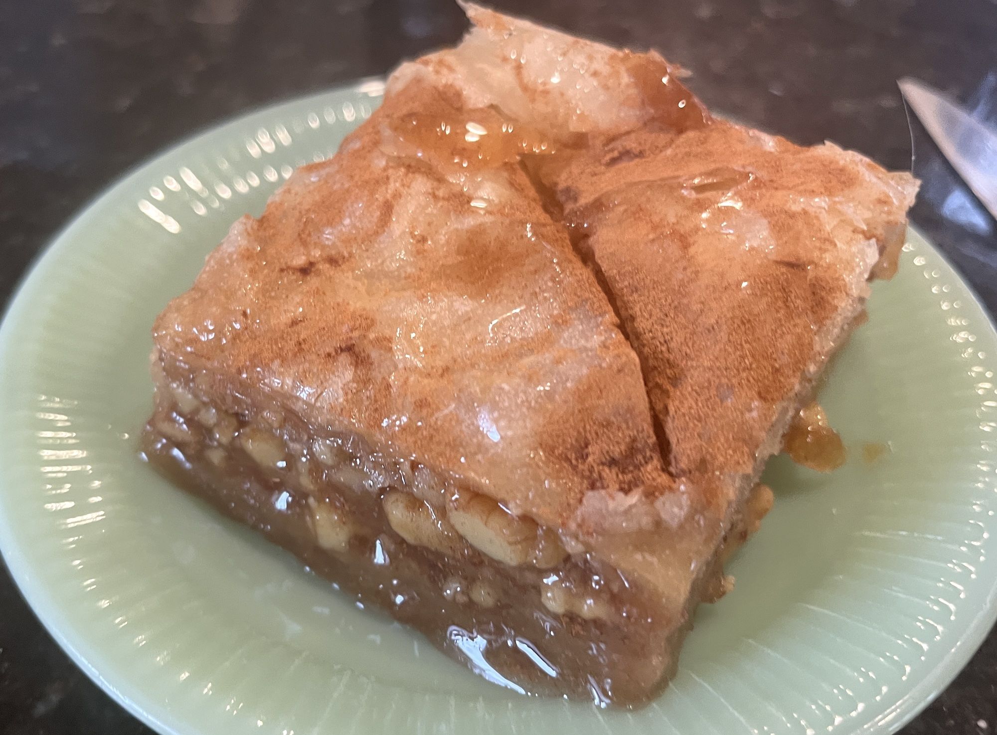 Square piece of baklava on green plate.