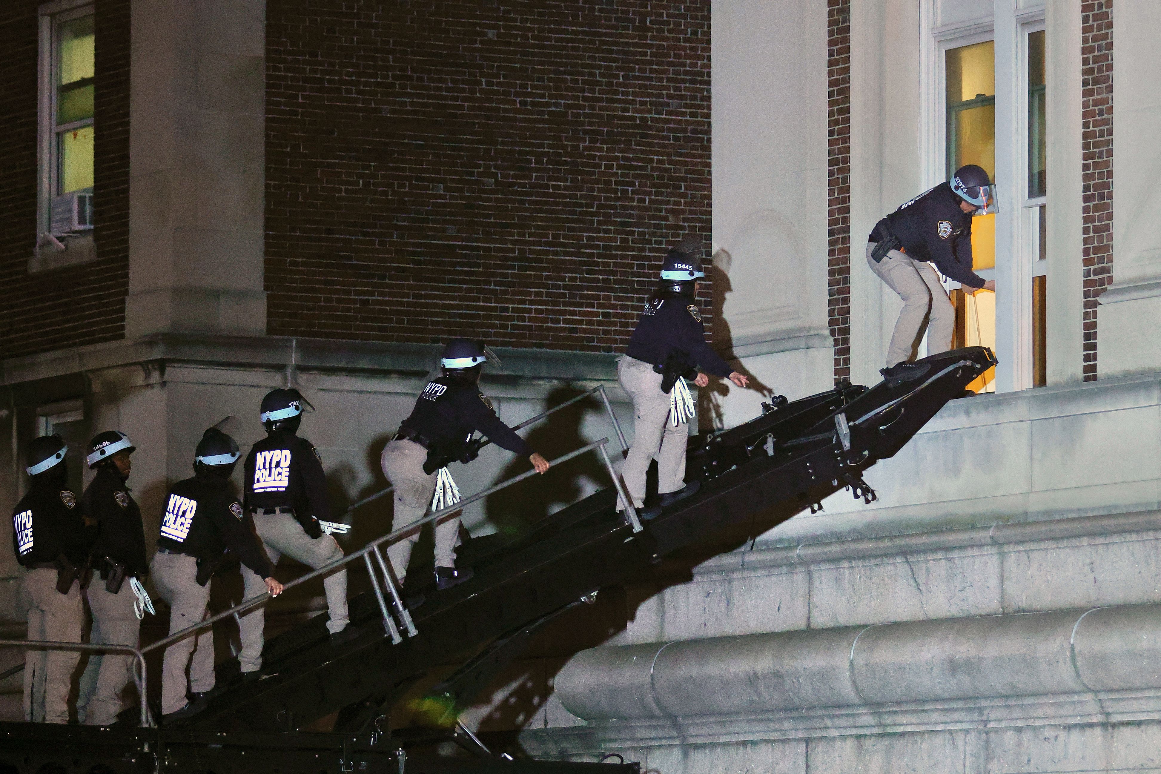 NYPD officers in riot gear break into a building at Columbia University, where pro-Palestinian students are barricaded inside a building and have set up an encampment, in New York City on April 30, 2024. Columbia University normally teems with students, but a "Free Palestine" banner now hangs from a building where young protesters have barricaded themselves and the few wandering through campus generally appear tense. Students here were among the first to embrace the pro-Palestinian campus encampment movement, which has spread to a number of universities across the United States