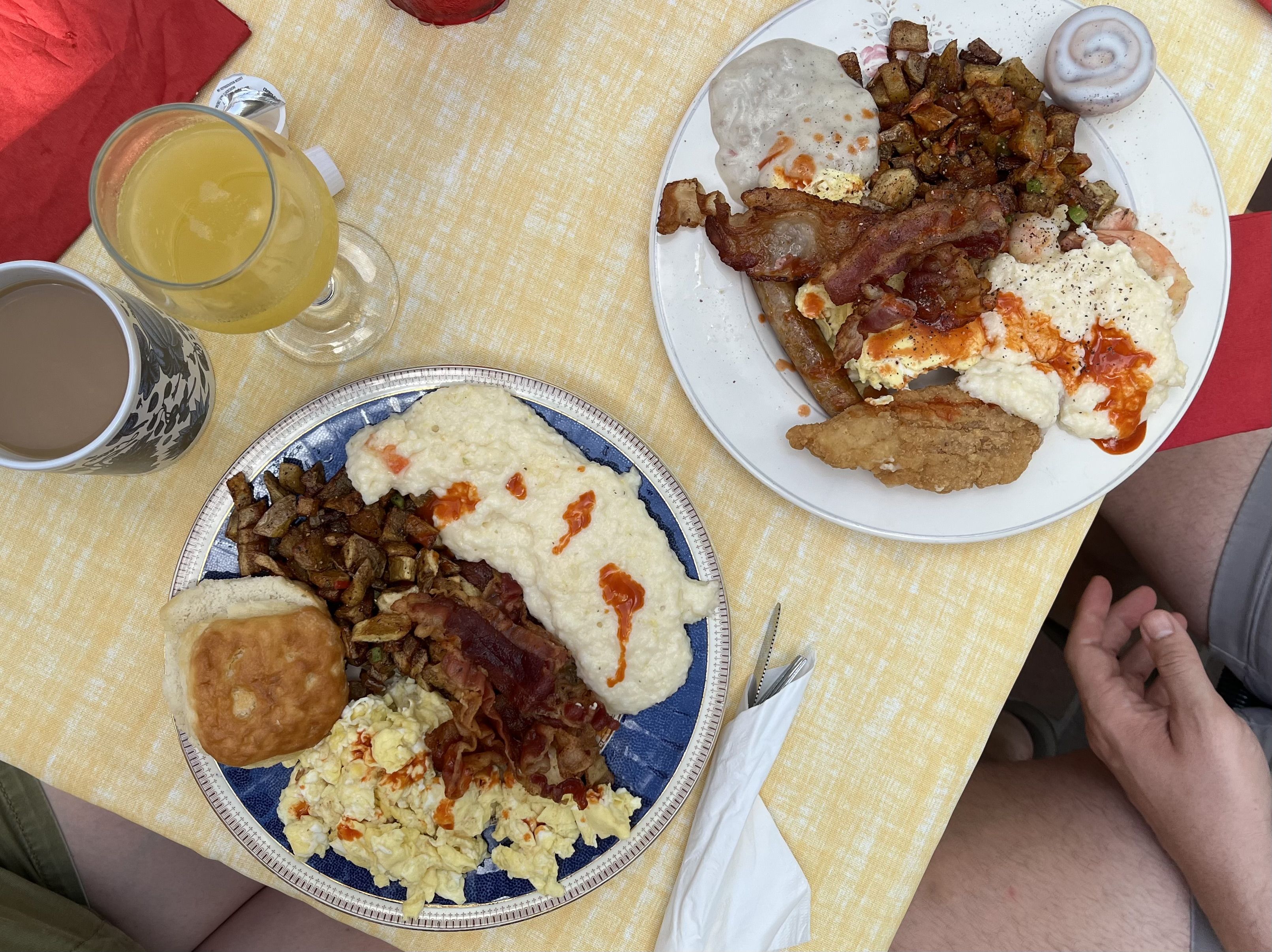An overhead photo showing plates of food with grits, bacon, potatoes, fried chicken, biscuits and gravy.