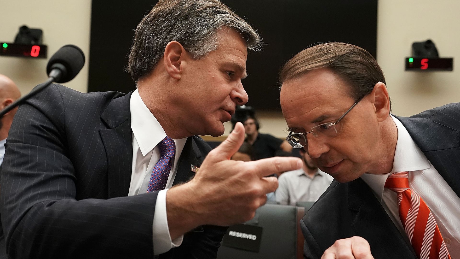 FBI director Christopher Wray leaning over to talk to Rod Rosenstein