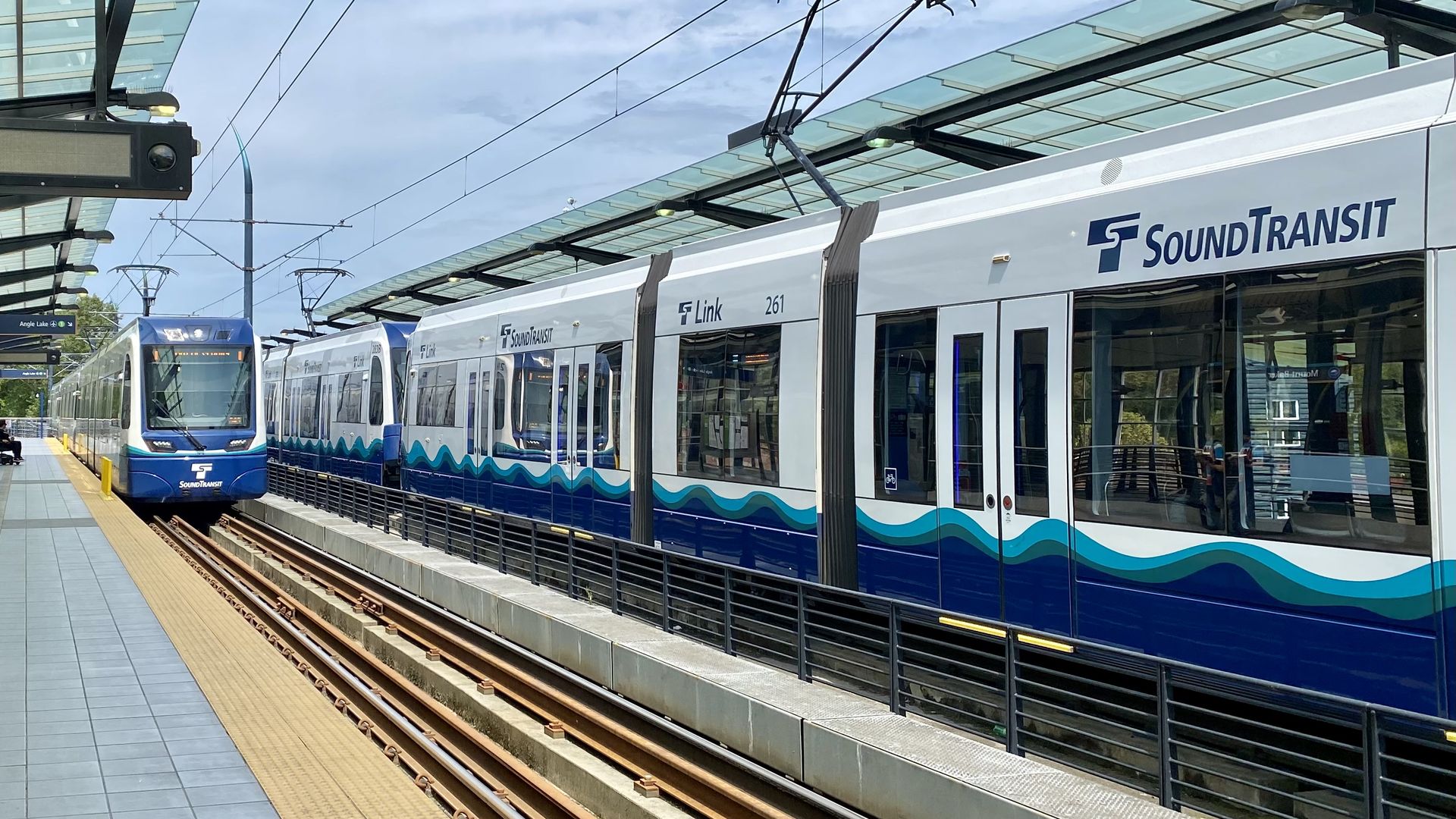 Two Sound Transit trains pass by one another at a train platform.