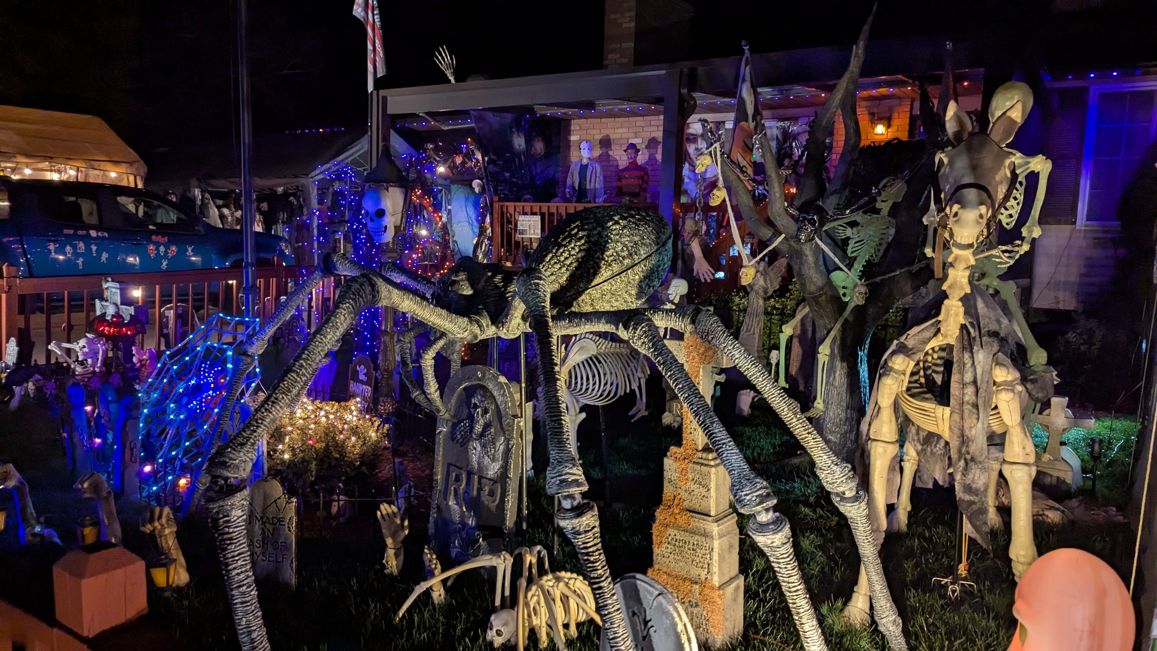 Spiders, skeletons and other Halloween decorations in a residential yard.