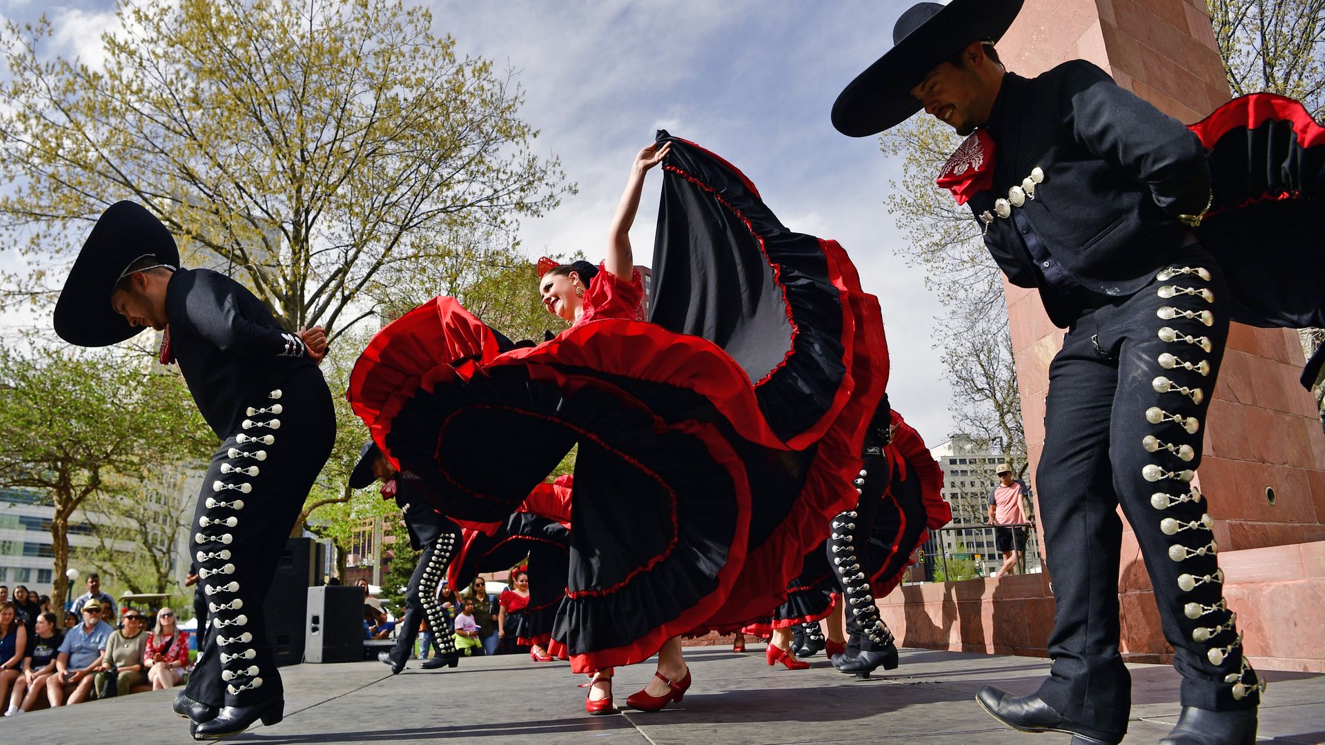 Traditional Mexican dancers during a performance in a sunny, outdoor arena.
