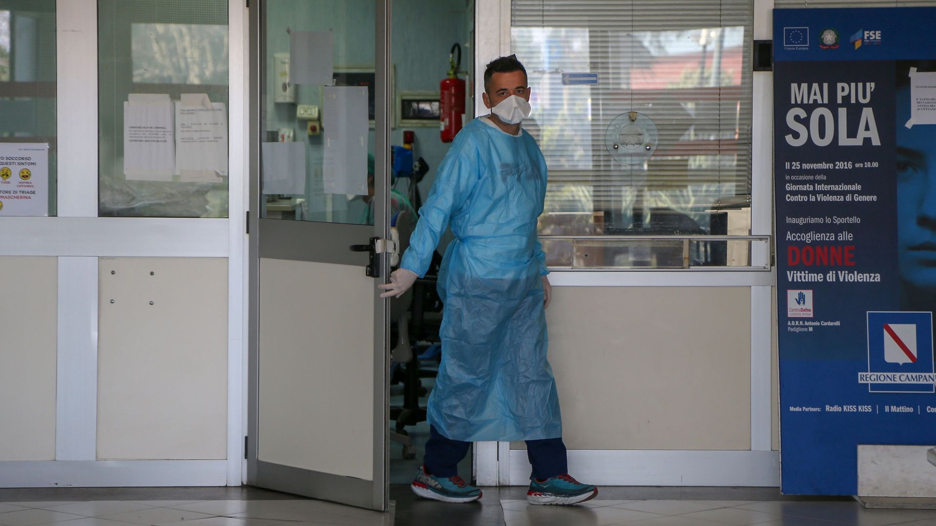 A hospital worker opens a door and leaves a room in an Italian hospital.