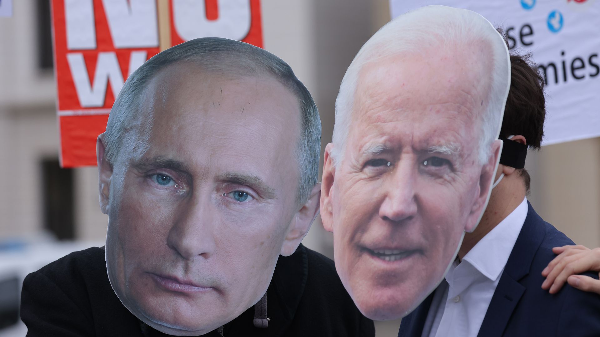 Cutout color images of Vladimir Putin and Joe Biden's faces are held by anti-war protesters in Berlin