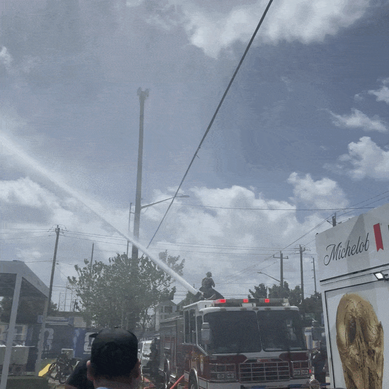 Houston fire fighters use a hose atop a fire truck to spray fans at Houston's FIFA Fan Fest