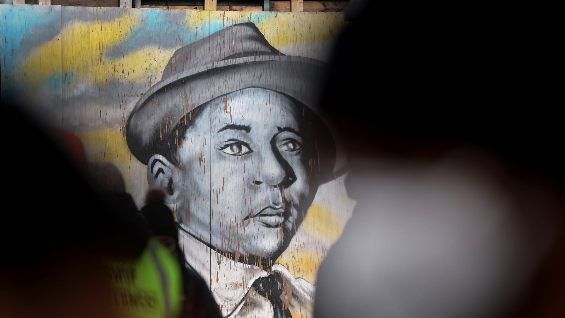Photo of a black and white mural of Emmett Till wearing a hat and looking upward mournfully