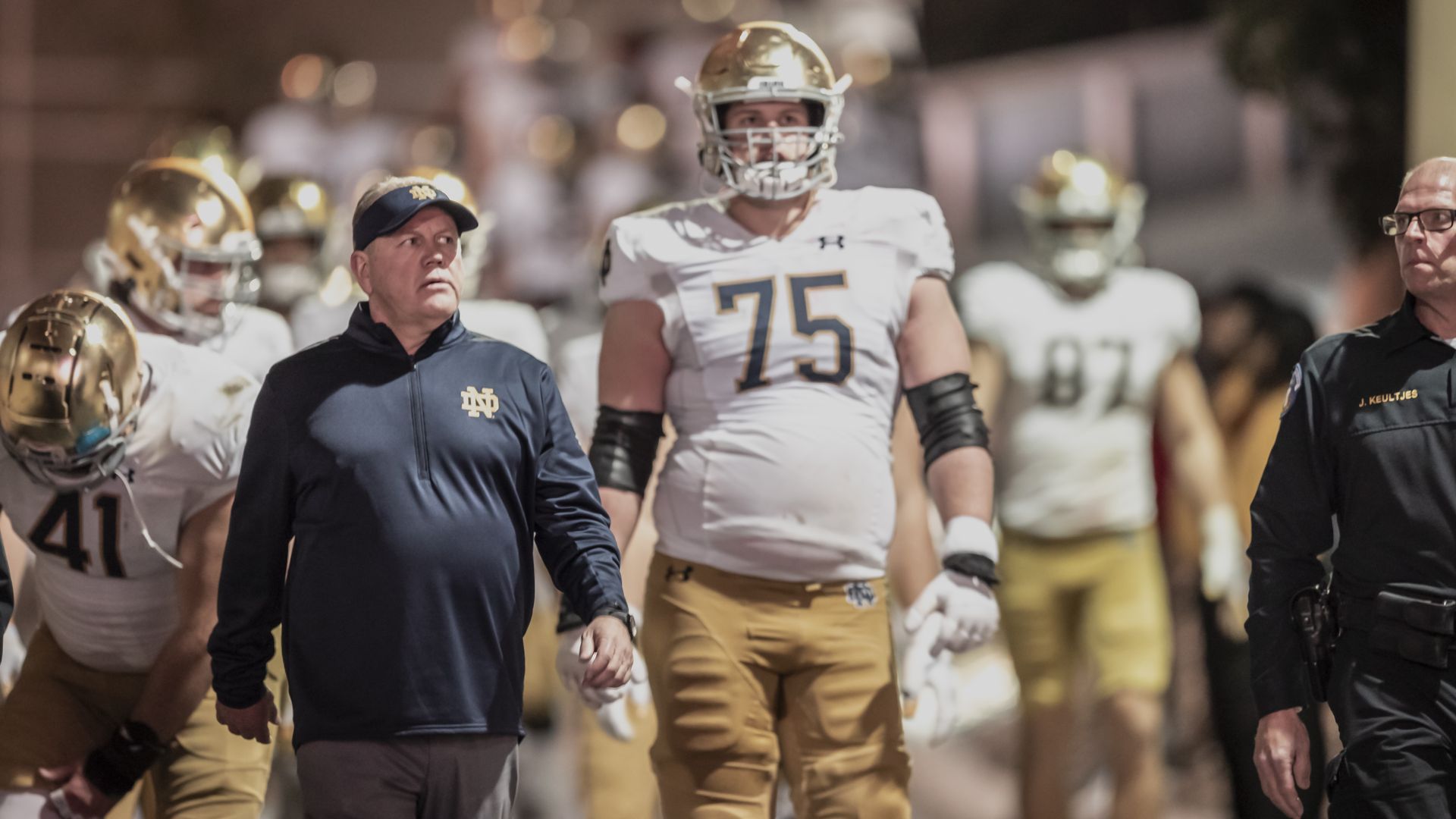 Former Notre Dame football coach Brian Kelly walks in front of his players