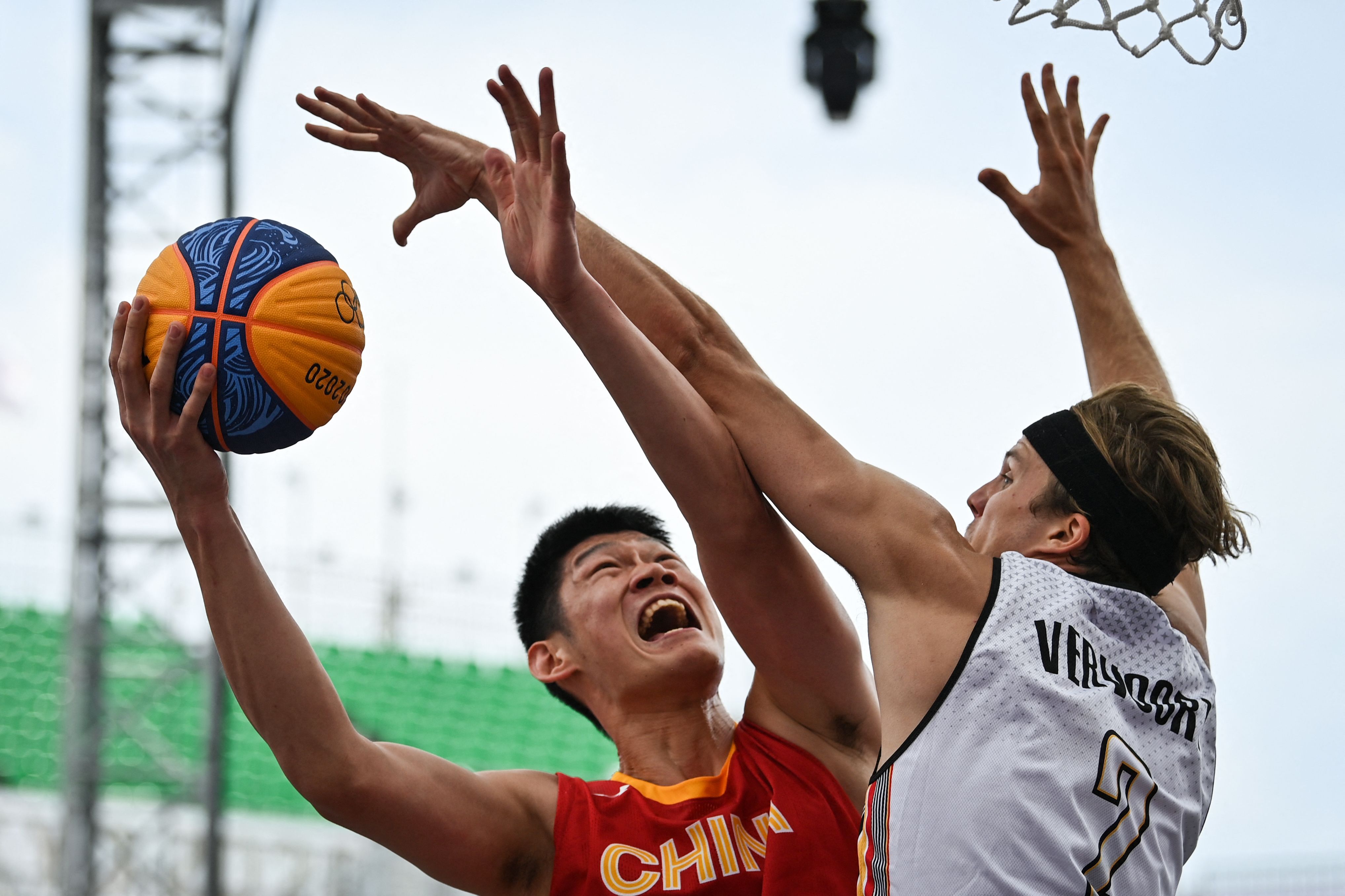 Belgium's Thibaut Vervoort (R) fights for the ball with China's Hu Jinqiu during the men's first round 3x3 basketball match between Belgium and China  in Tokyo, on July 26