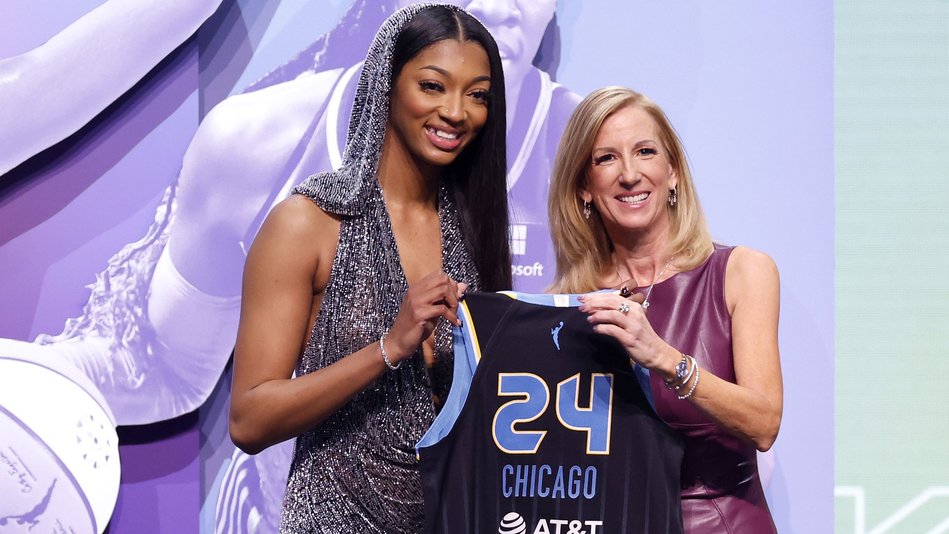 Photo shows Angel Reese and the WNBA commissioner holding up a Chicago Sky jersey after Reese was drafted.