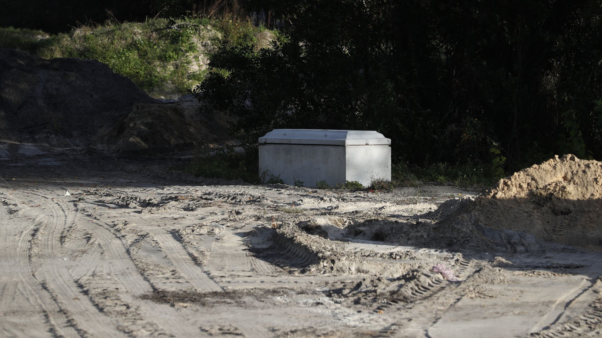 A lone headstone sits on sand