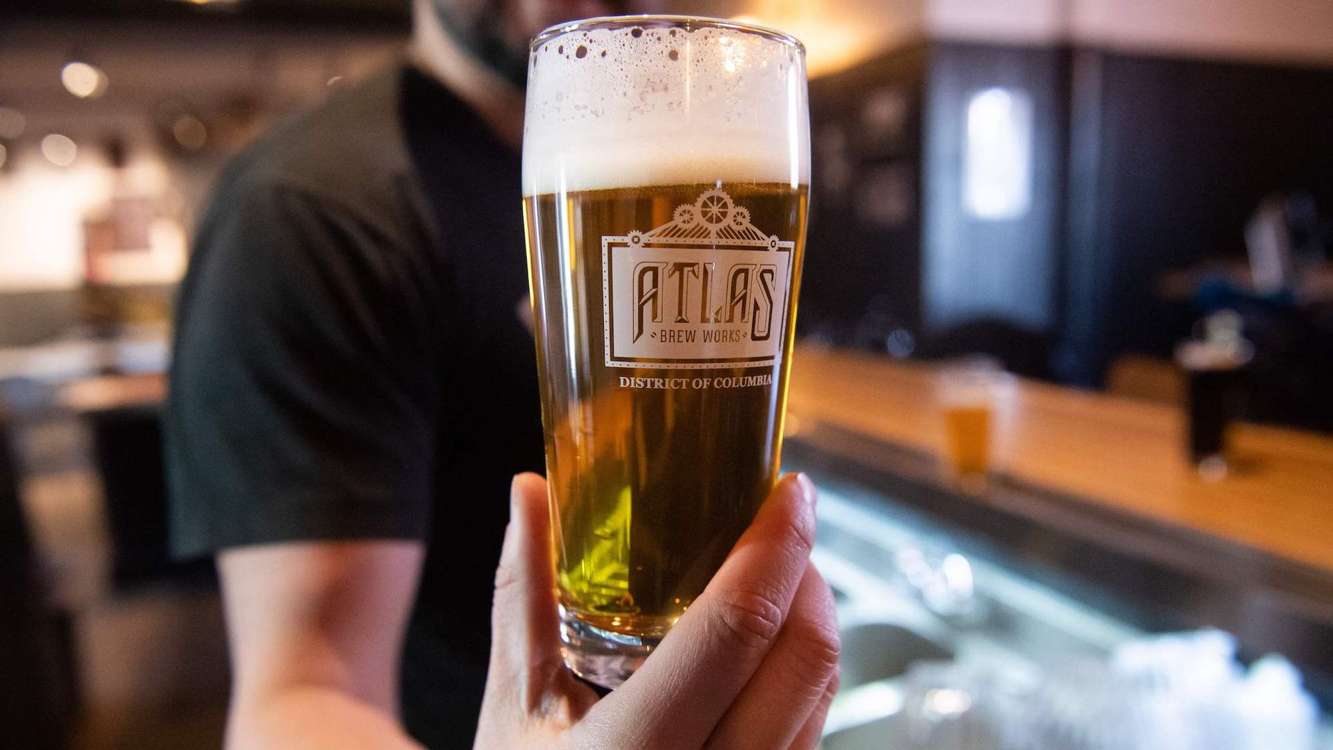 A man holding a pint of Atlas beer