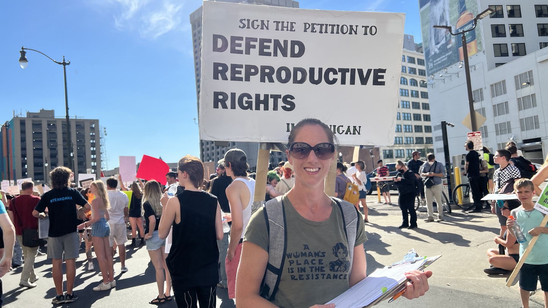 Ballot initiative circulator wearing large sign that says "Sign the Petition to Defend Reproductive Rights."