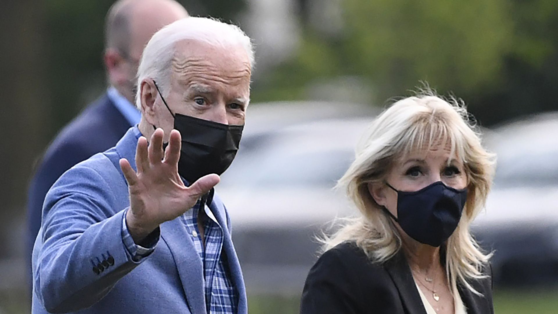 Biden waives while wearing a mask upon returning to the White House