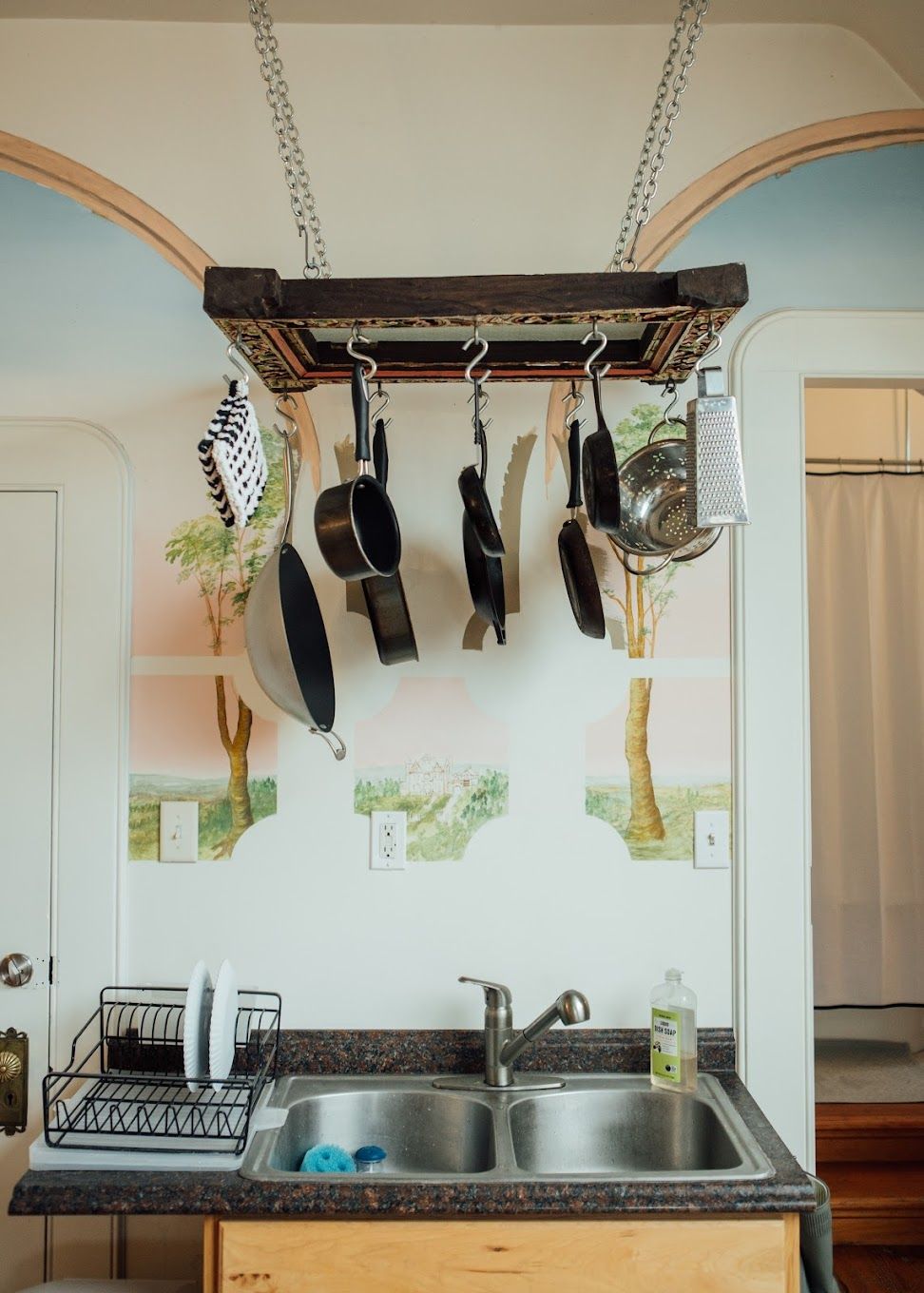 A photo of a kitchen with pink and green murals on the walls.