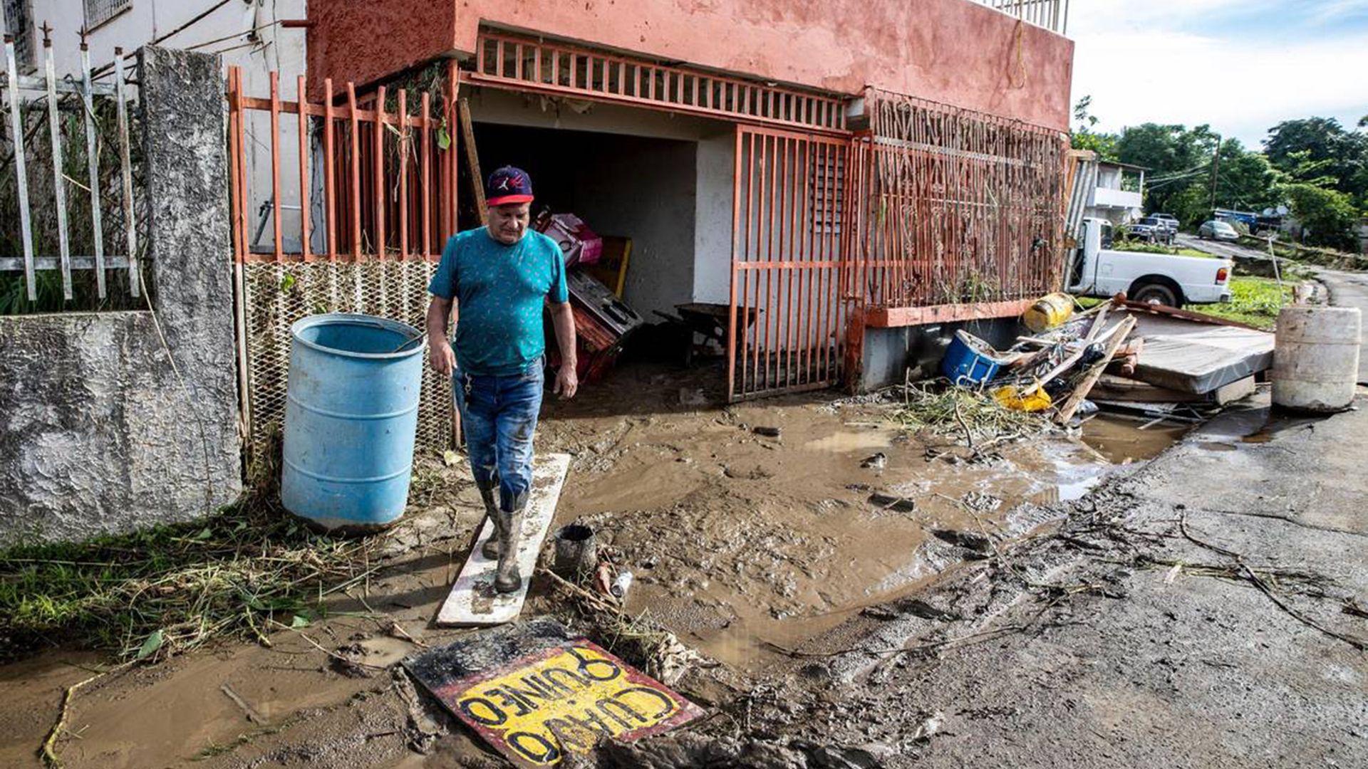A man looks down while walking amid mud outside his home in Puerto Rico 