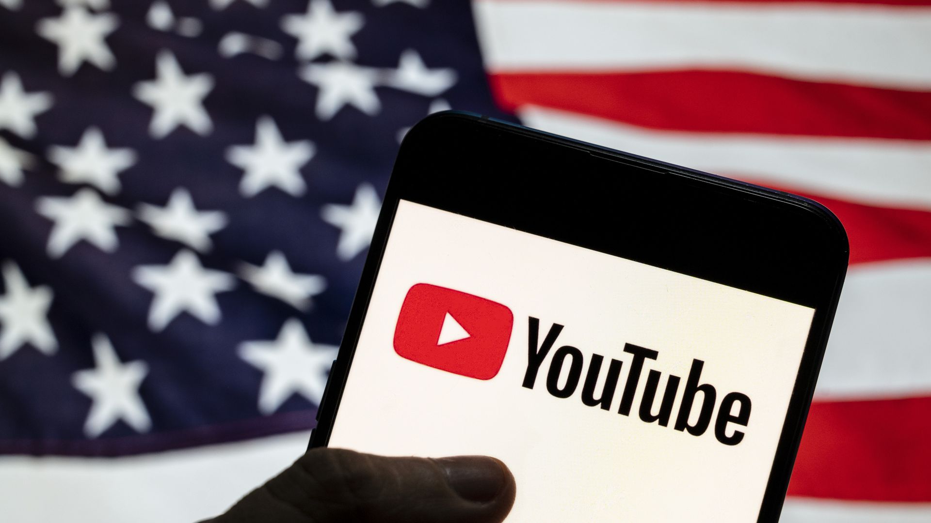 A photo illustration of a YouTube logo on a smartphone against an American flag background