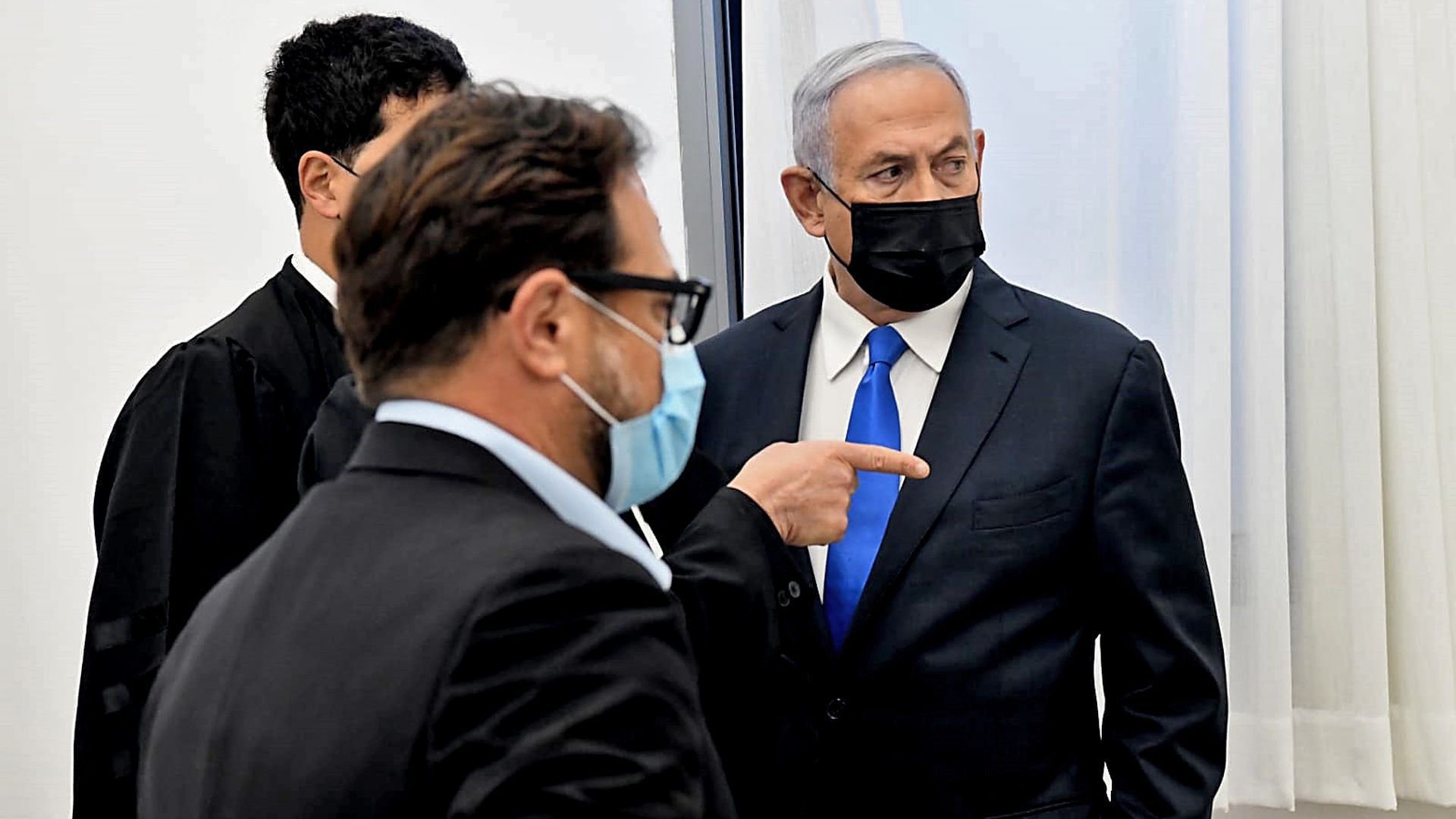 Israeli Prime Minister Benjamin Netanyahu (R) talks to his lawyers ahead of a hearing in his corruption trial at the Jerusalem district court