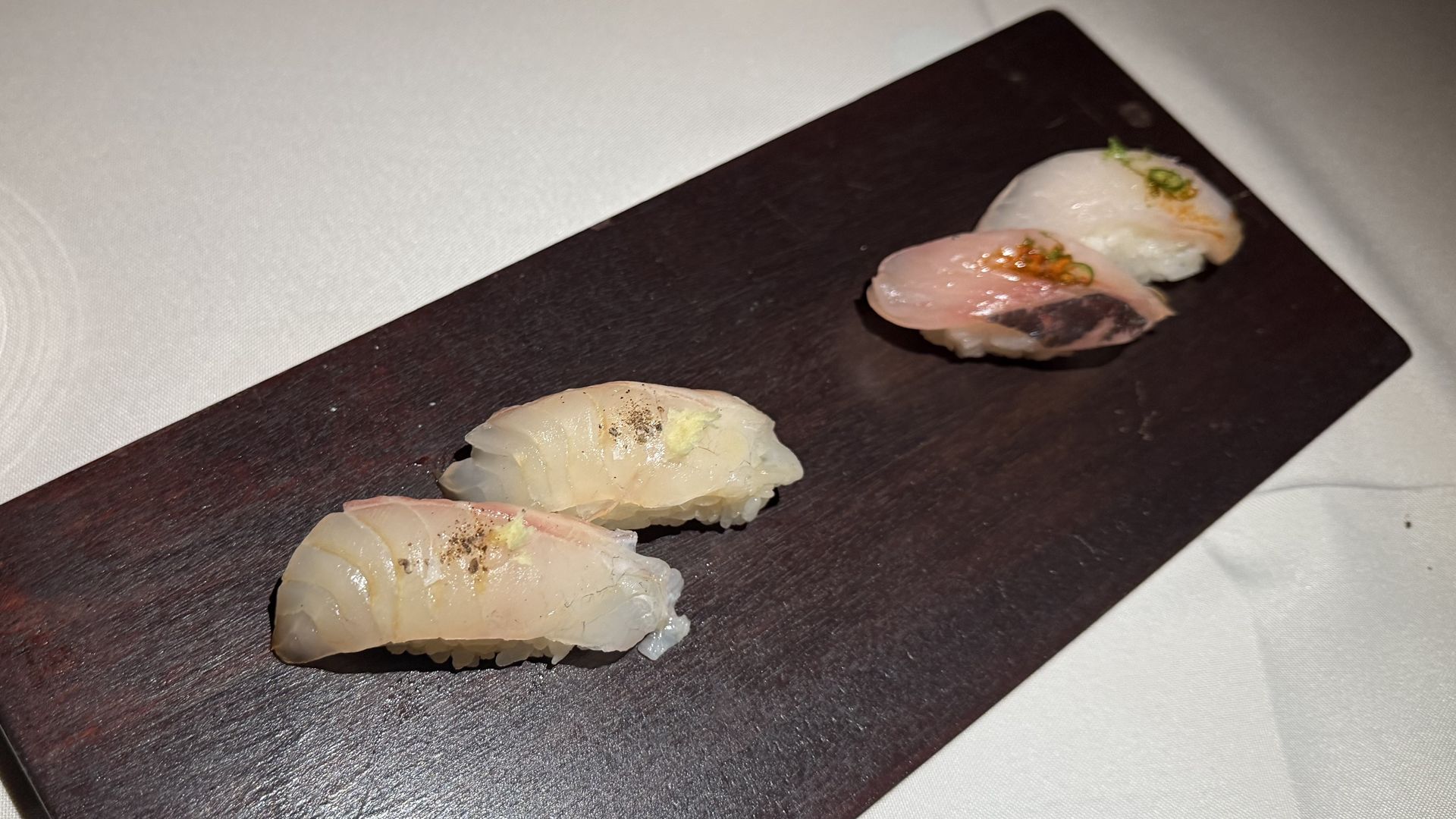 Four pieces of sushi on a dark piece of wood. 