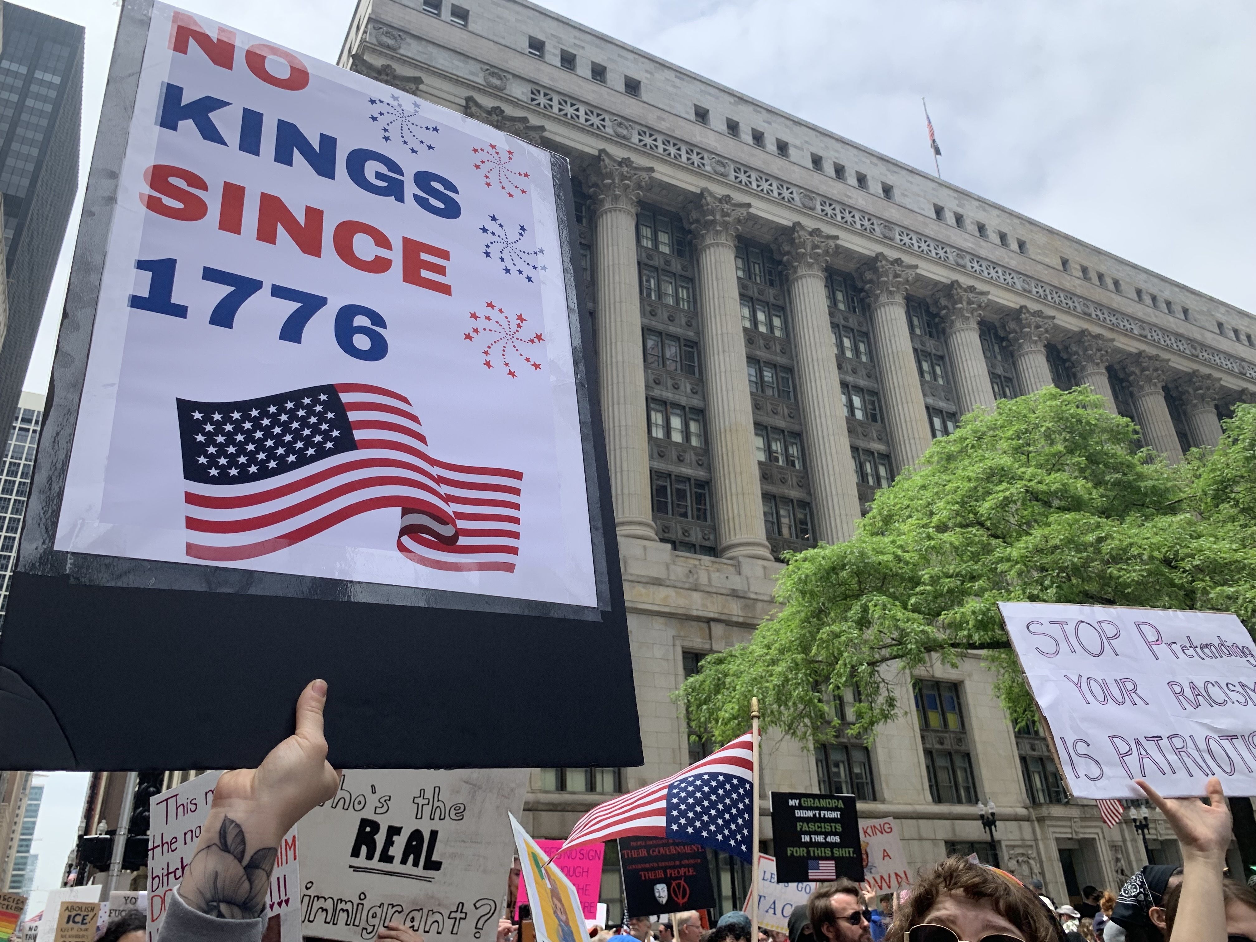 Protesters fill up a plaza with signs and march on a street. 