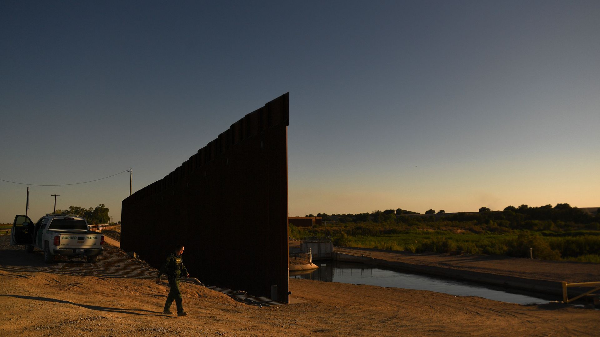 A Border Patrol agent walking between a gap along a wall between the U.S.-Mexico border in Yuma, Arizona in June 2022.