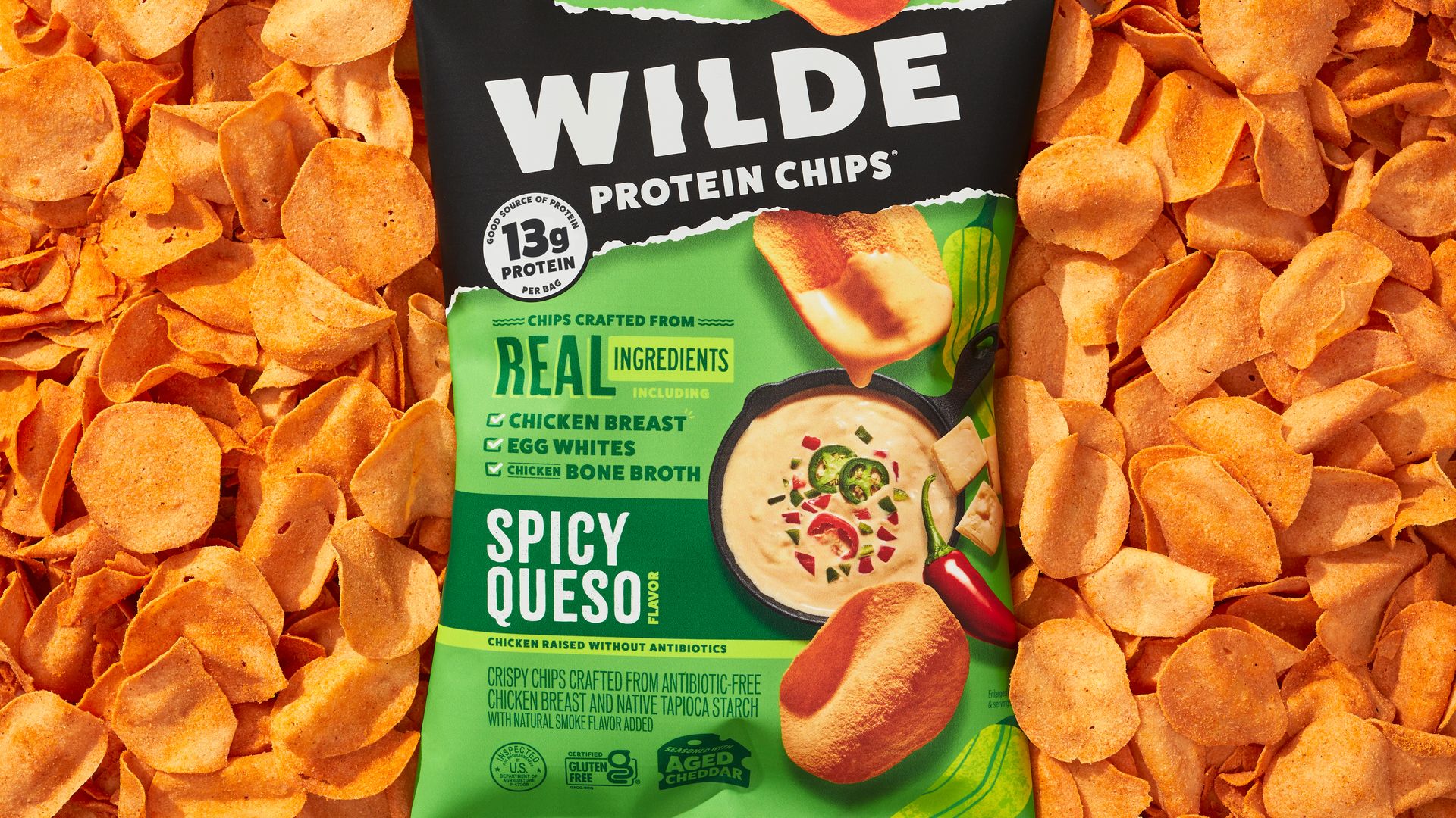 A bag of snack chips made from chicken sits on top of snacking chips spread out over a surface.