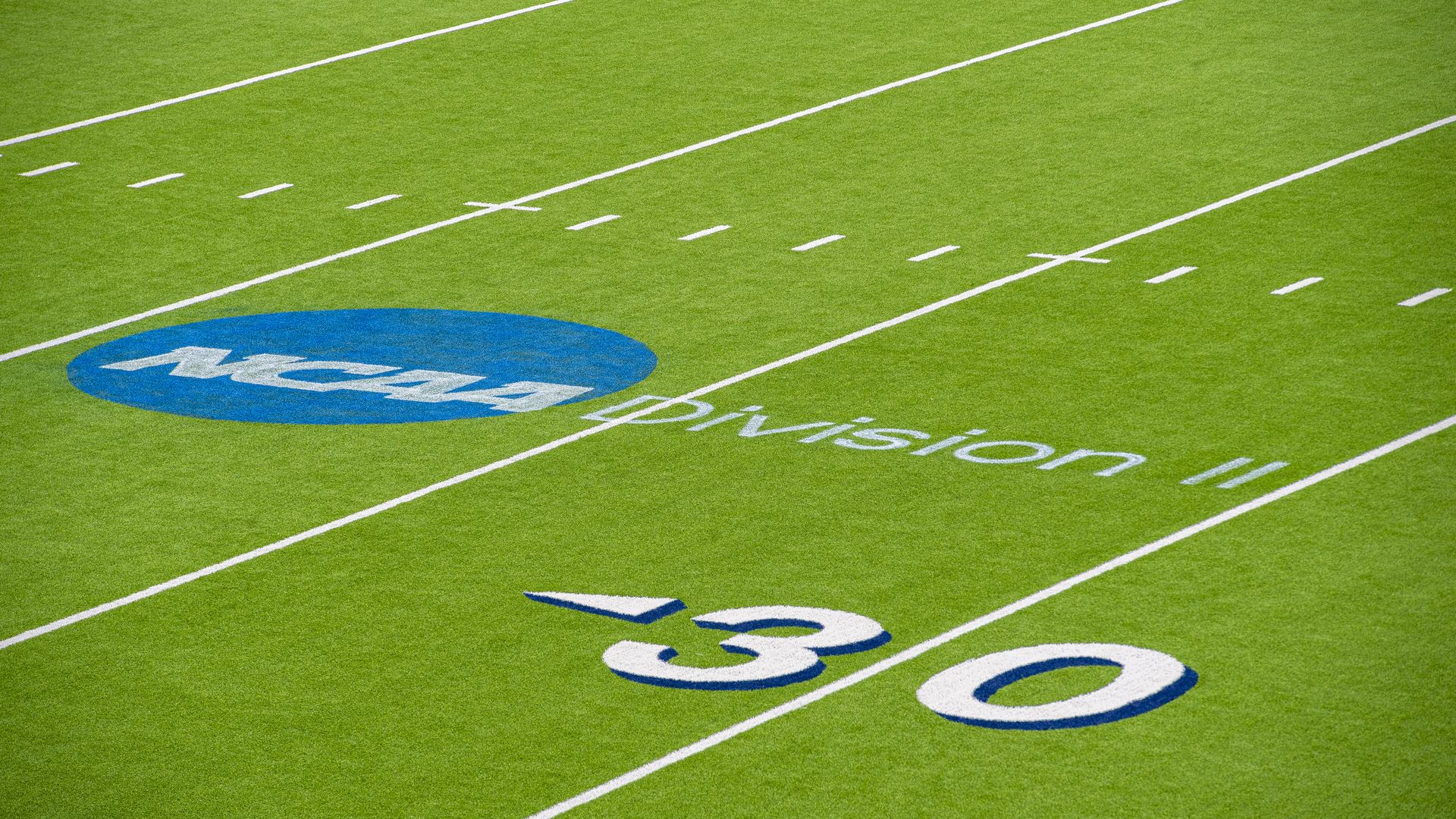 The NCAA Division II logo on a football field by the 30-yard line
