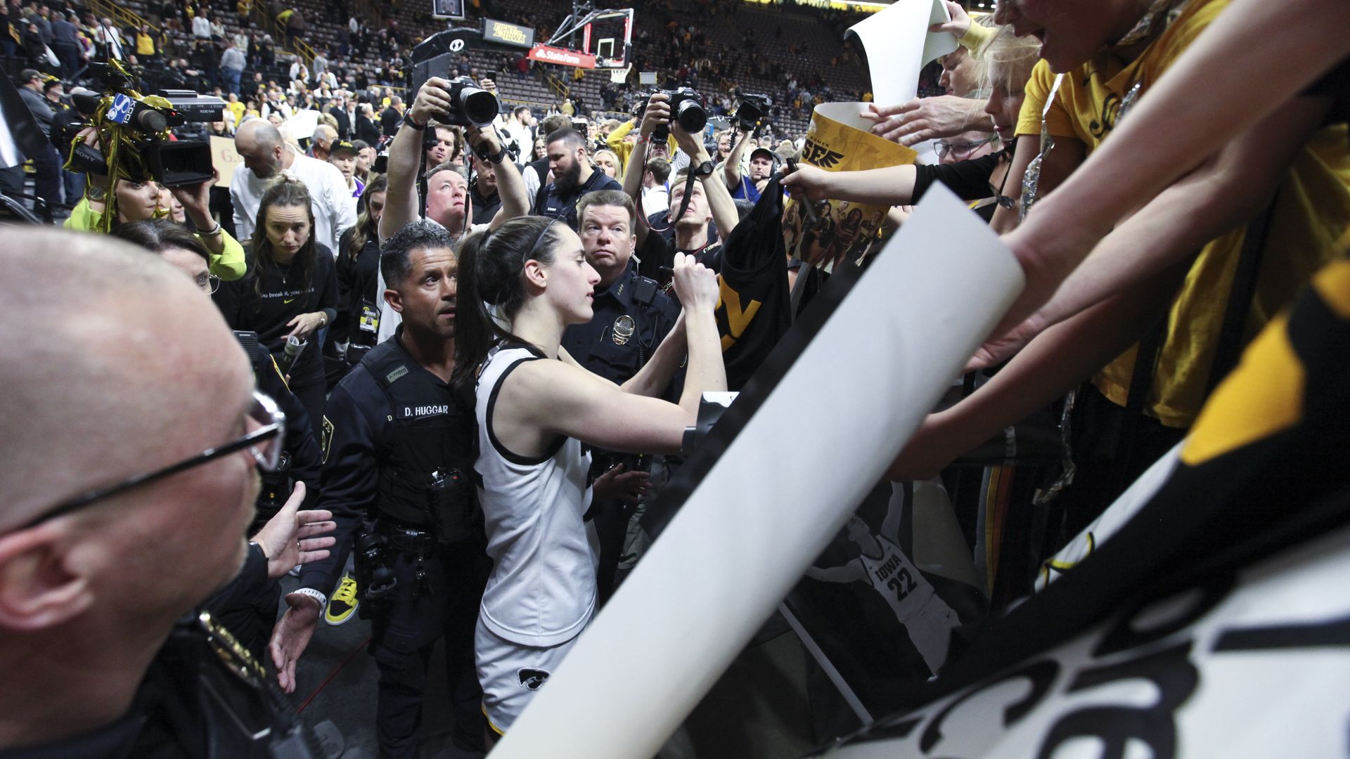 Caitlin Clark signing autographs in a crush of cameras and fans