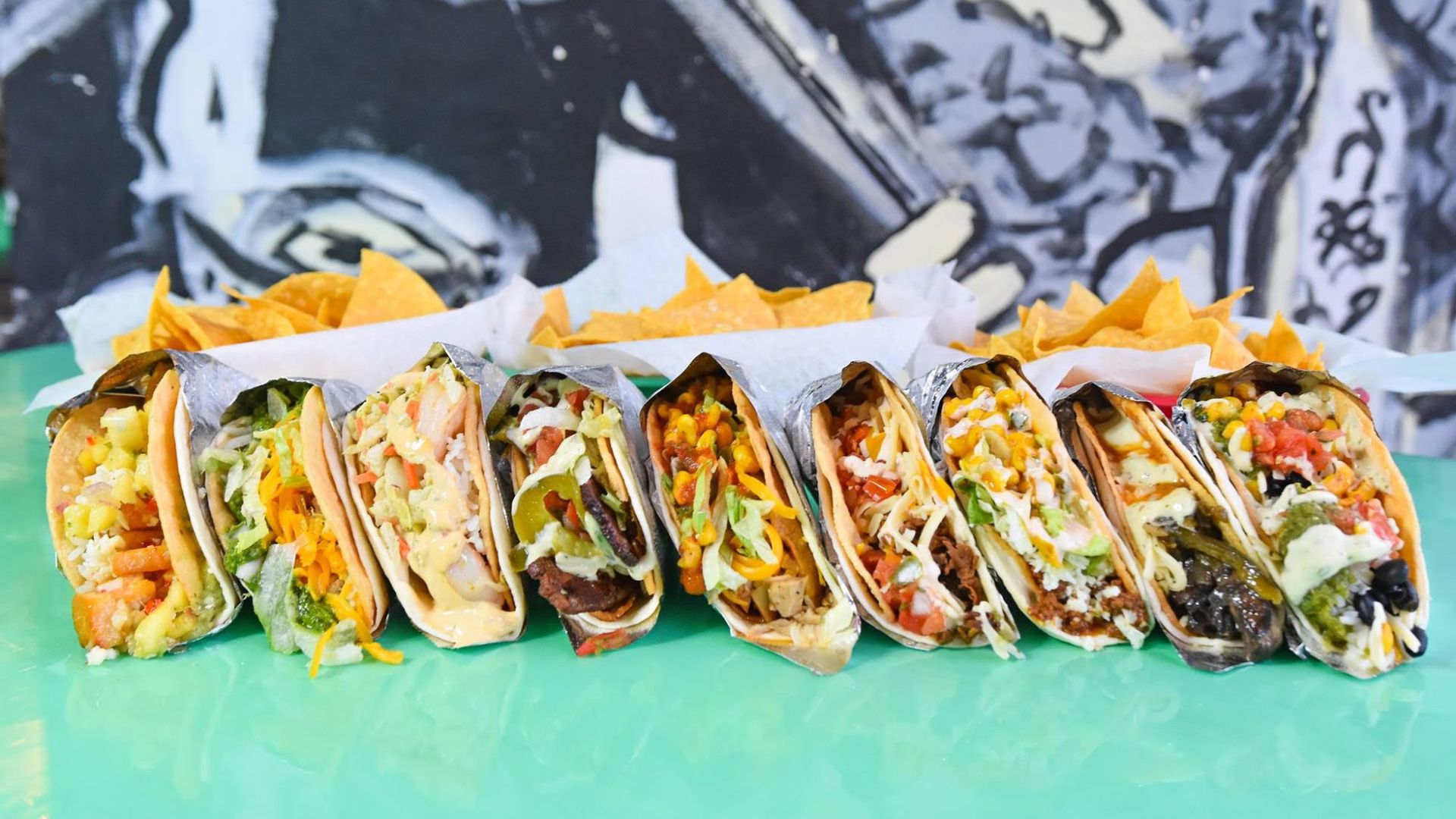 A row of tacos with a variety of toppings