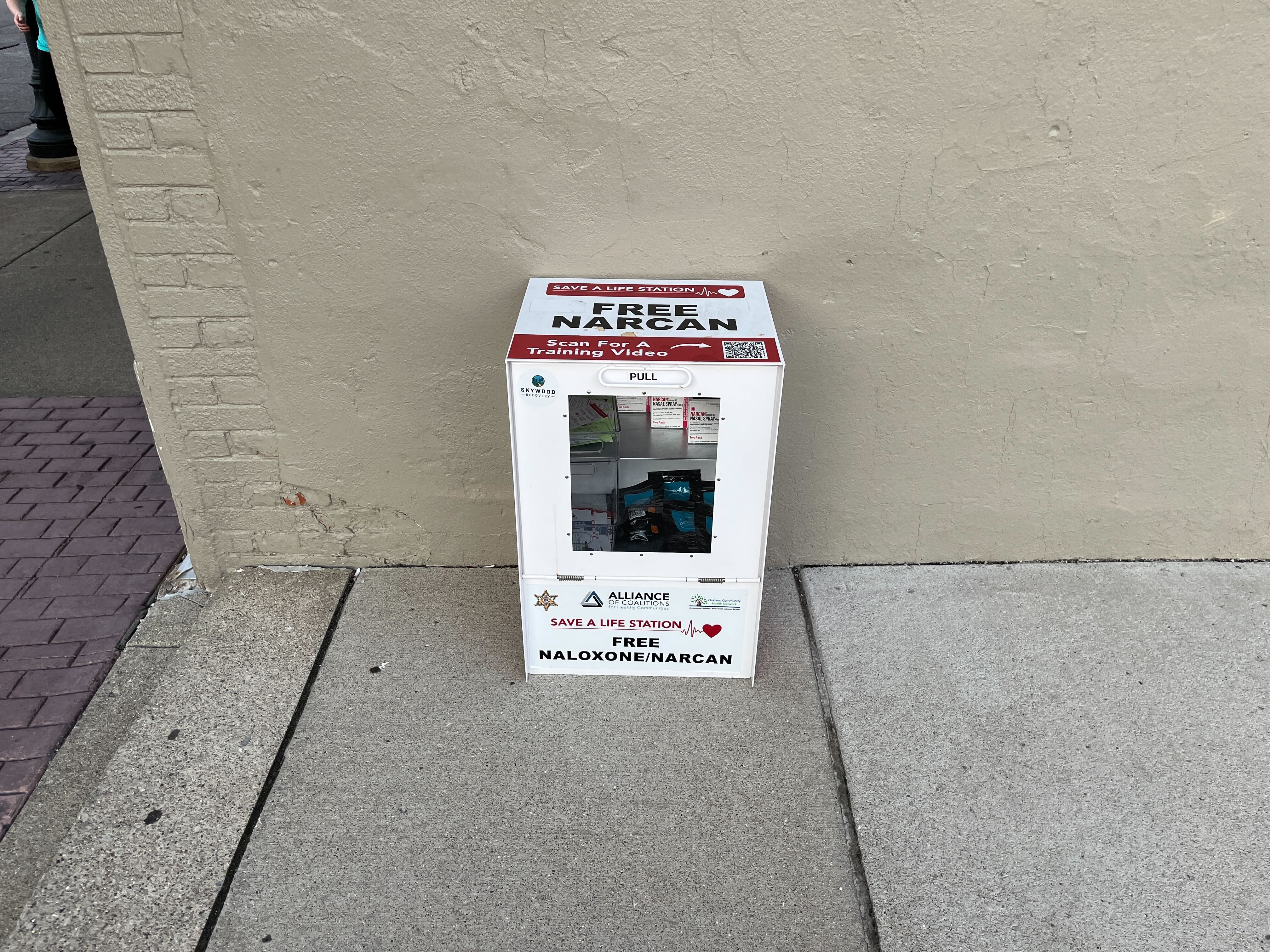 A box that says "free Narcan" on a sidewalk. 