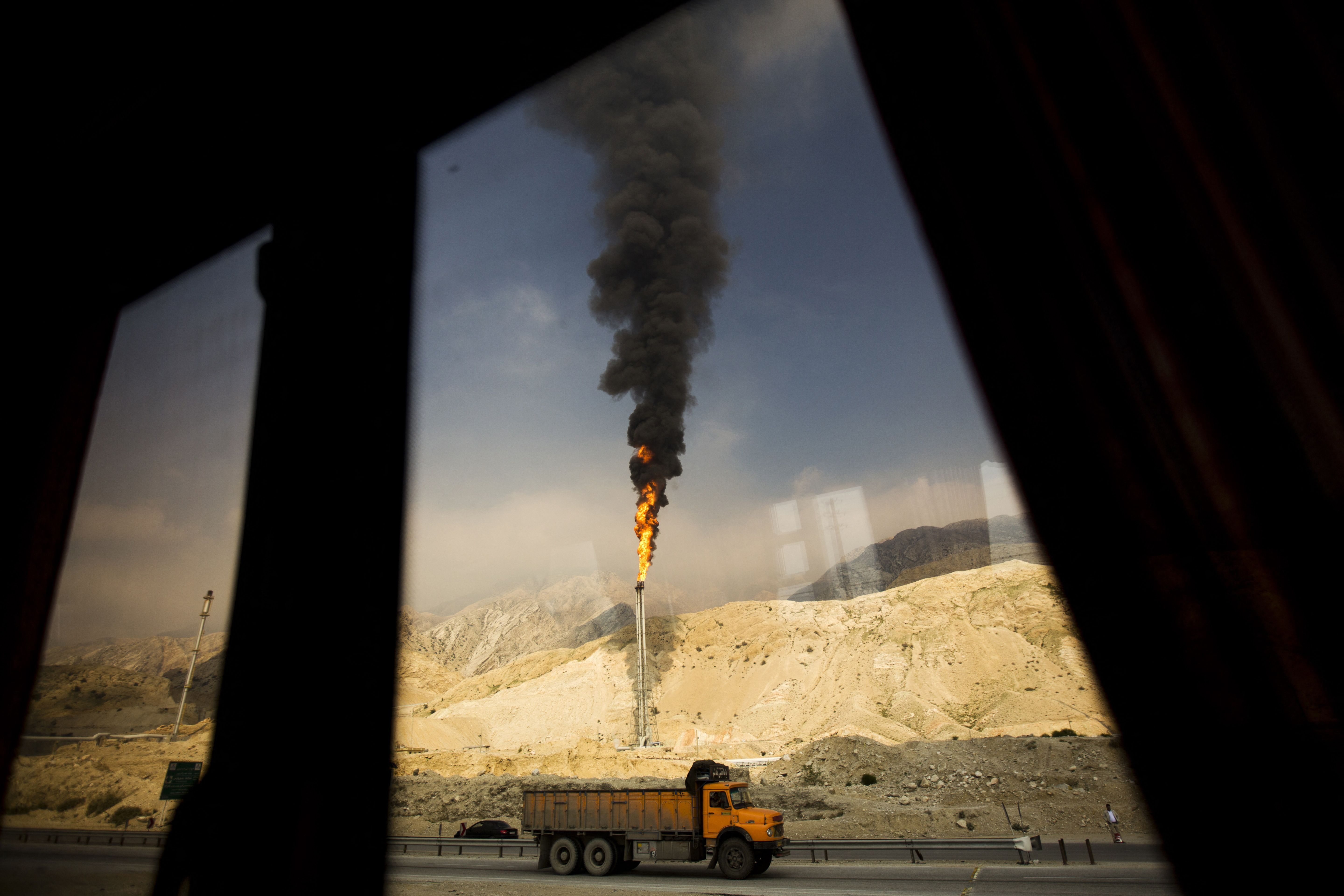 Gas flames rise from industrial facilities at Iran’s South Pars field, seen through a bus window in Assaluyeh.