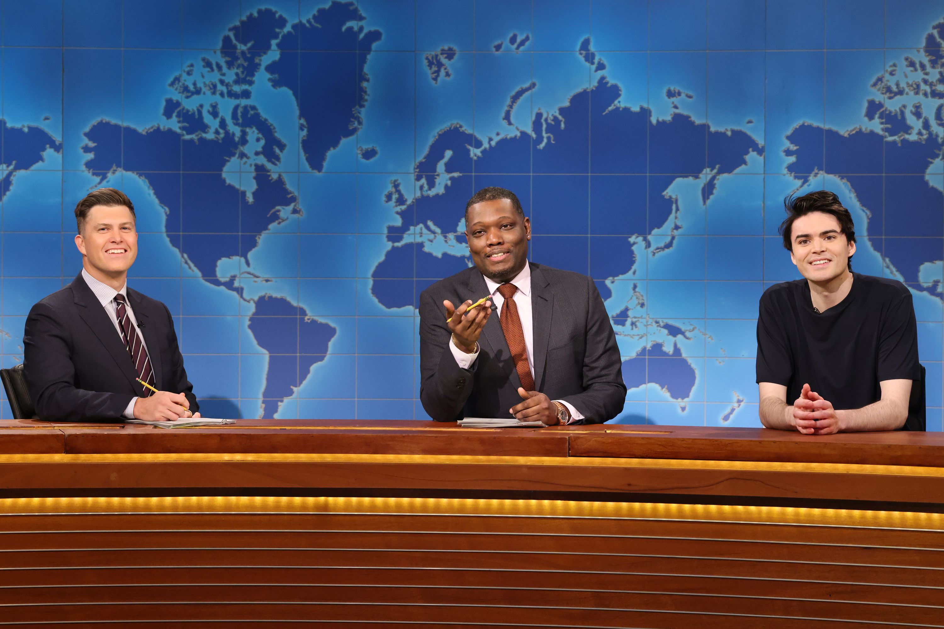 Three people sitting at a news desk.