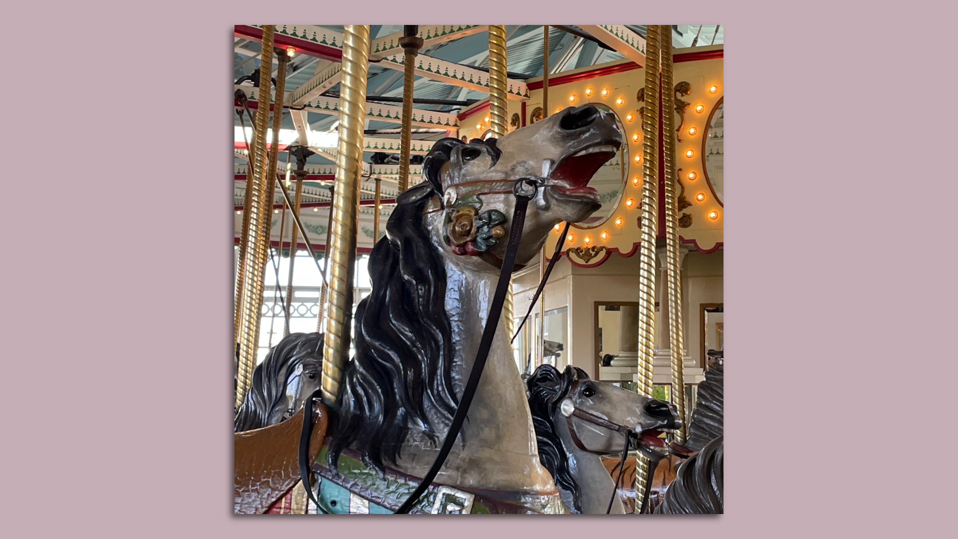 A grey antique carousel horse with a black mane
